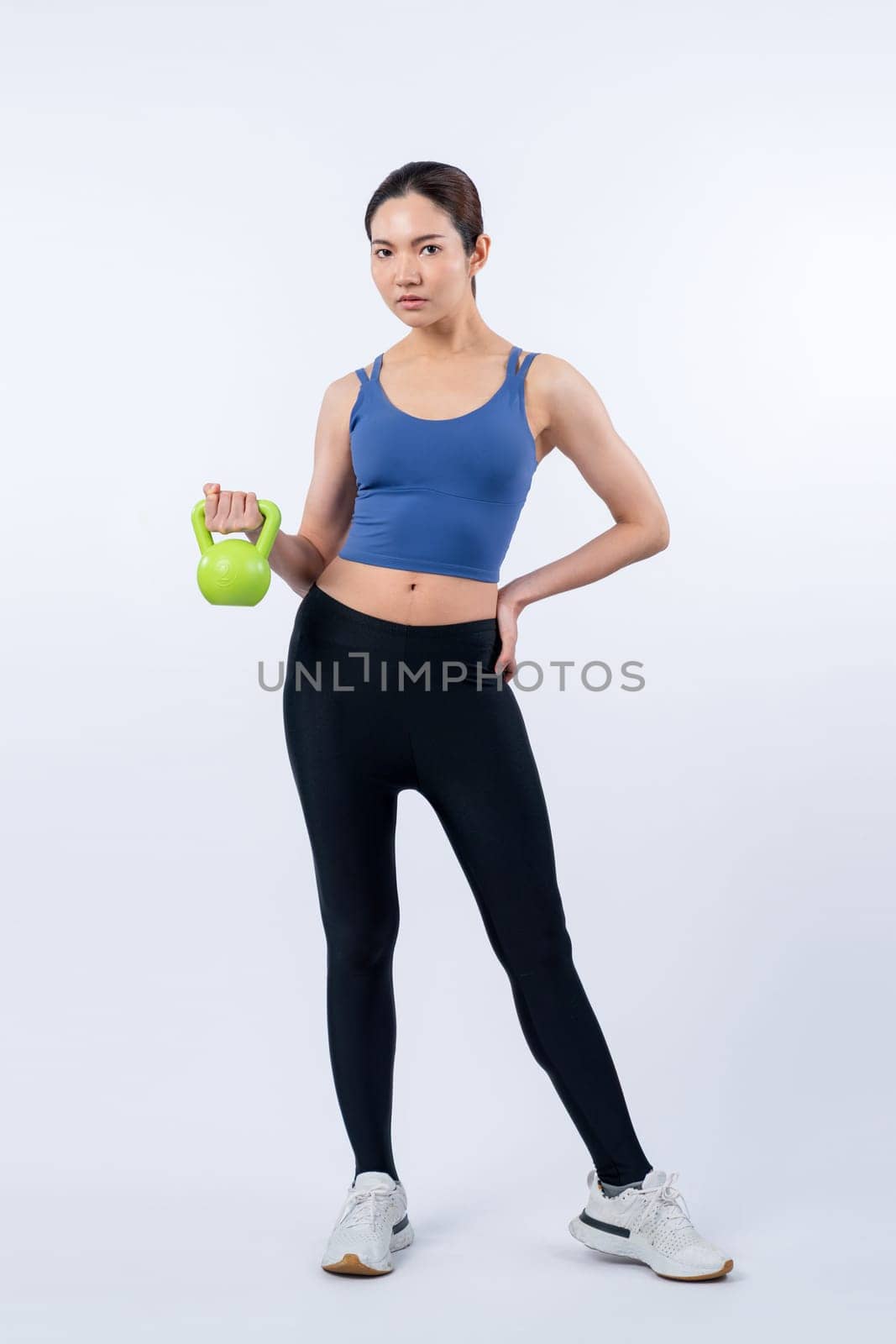 Vigorous energetic woman doing yoga with kettlebell weight exercise. by biancoblue