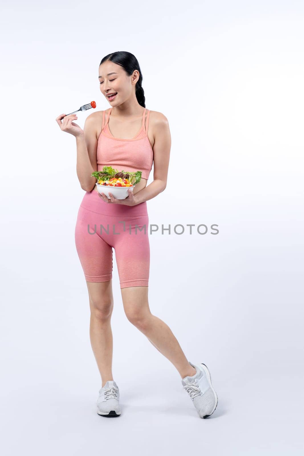 Asian woman in sportswear holding salad bowl on isolated background. Vigorous by biancoblue