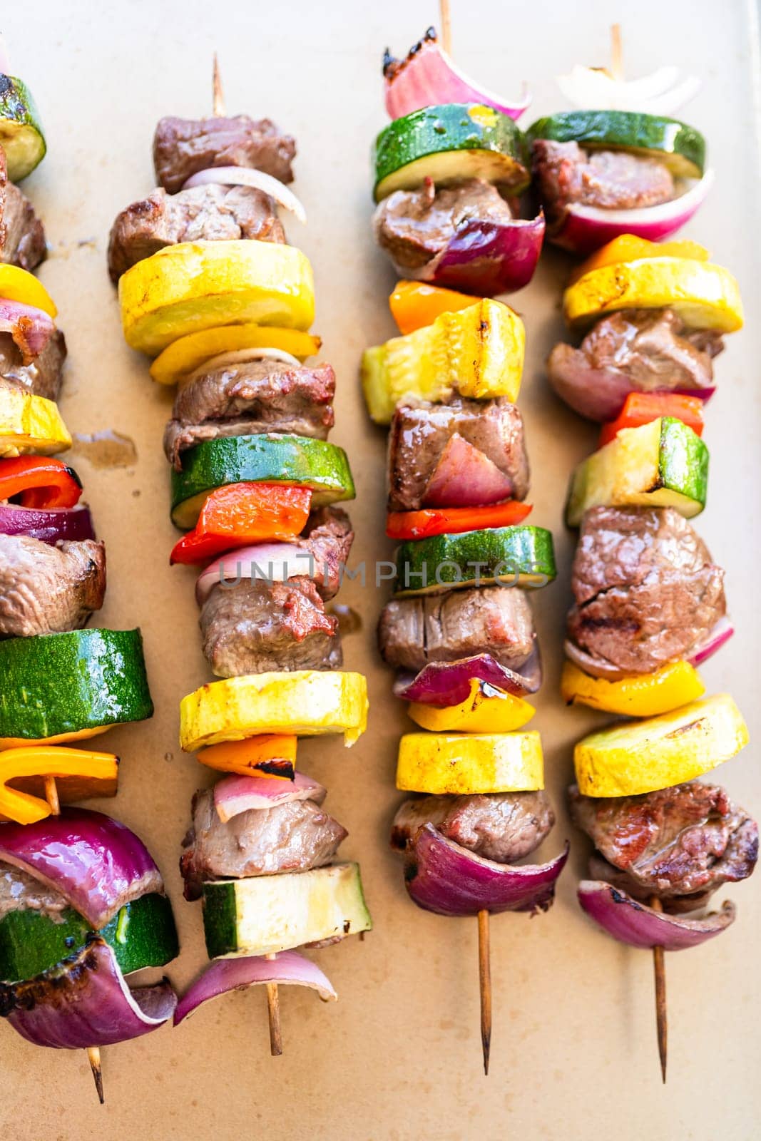 Flavorful beef and colorful veggie skewers, marinated and grilled to perfection, sizzling on a baking sheet.