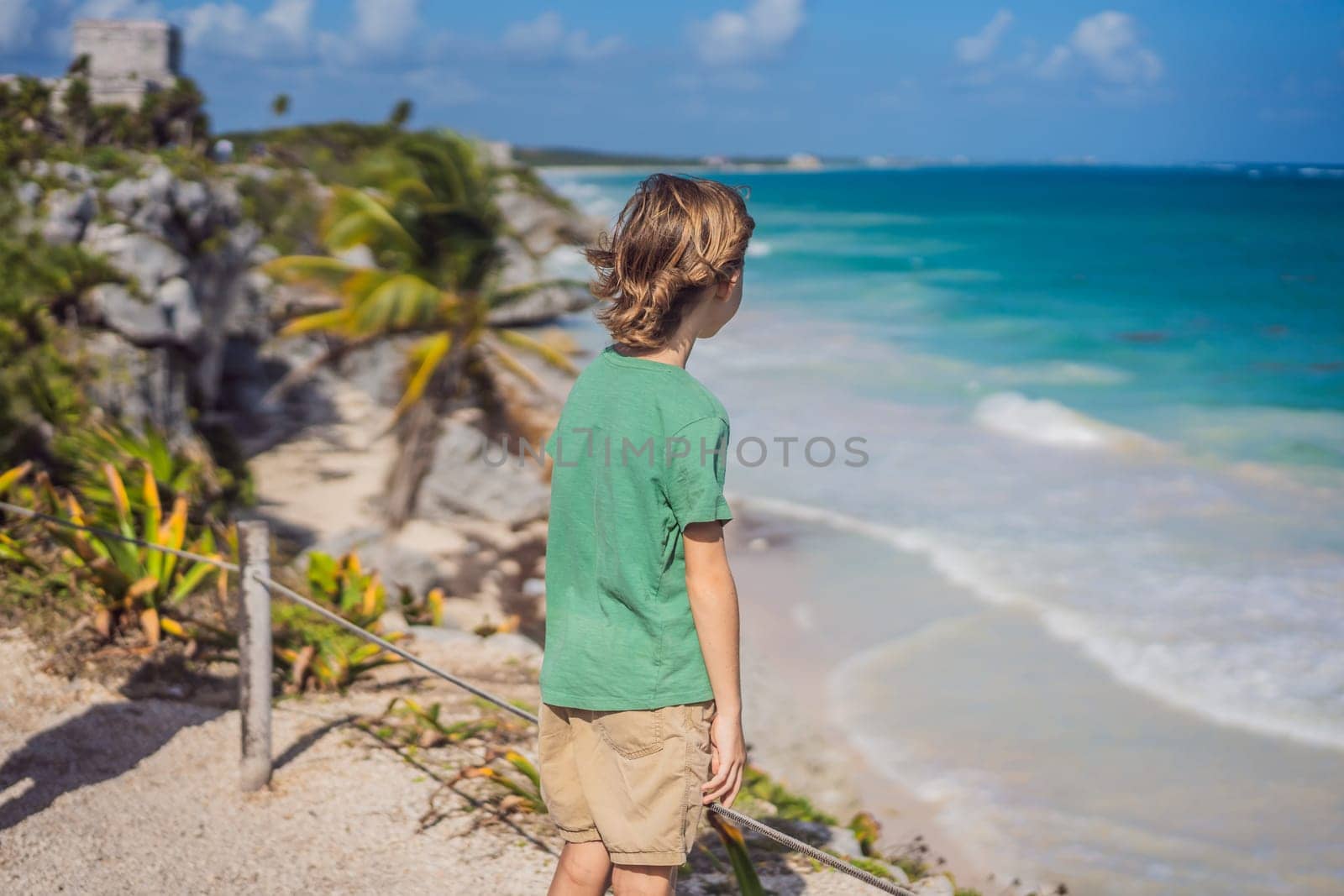 Boy tourist enjoying the view Pre-Columbian Mayan walled city of Tulum, Quintana Roo, Mexico, North America, Tulum, Mexico. El Castillo - castle the Mayan city of Tulum main temple.