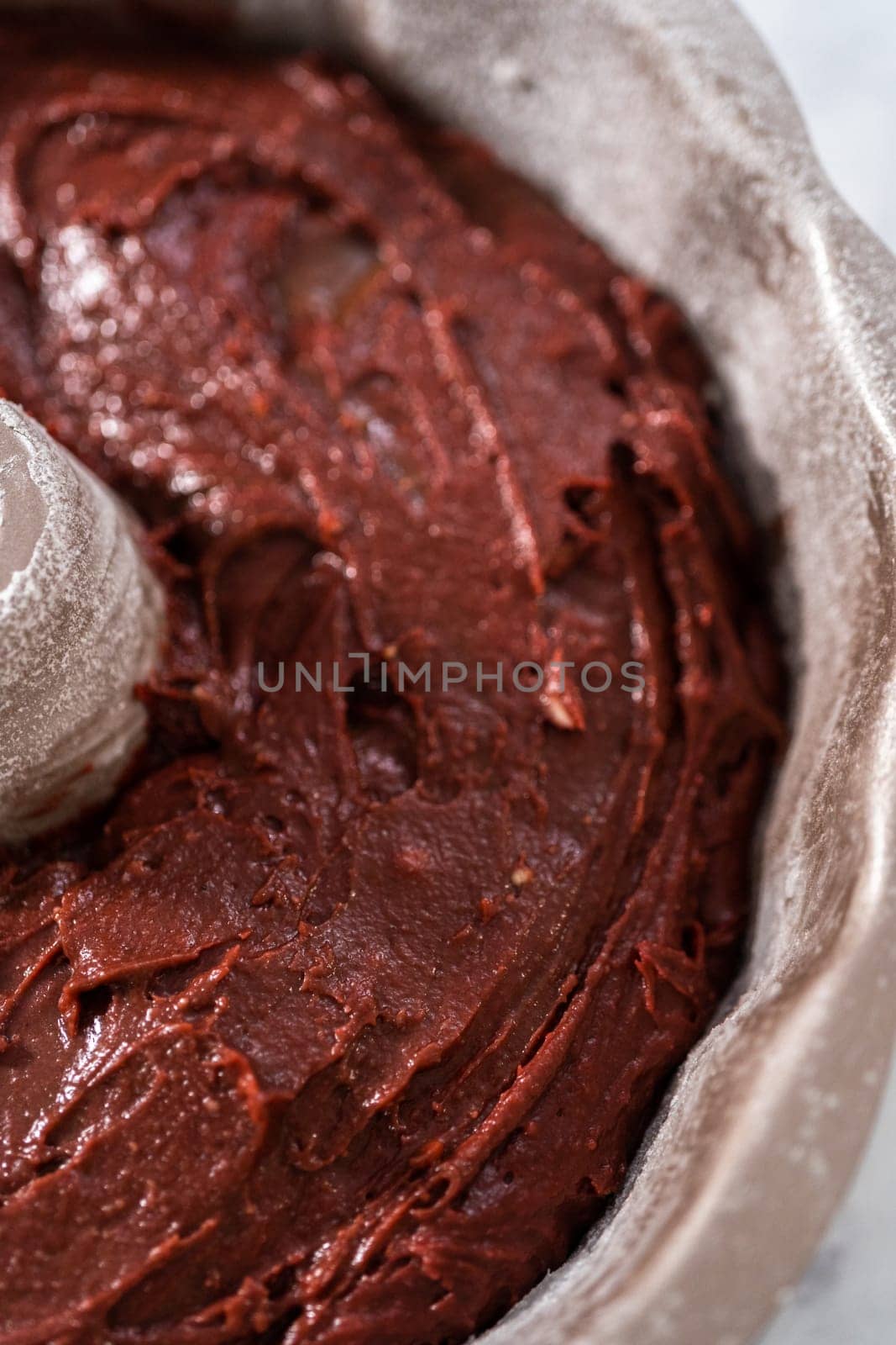 Filling metal bundt cake pan with cake butter to bake red velvet bundt cake with cream cheese glaze