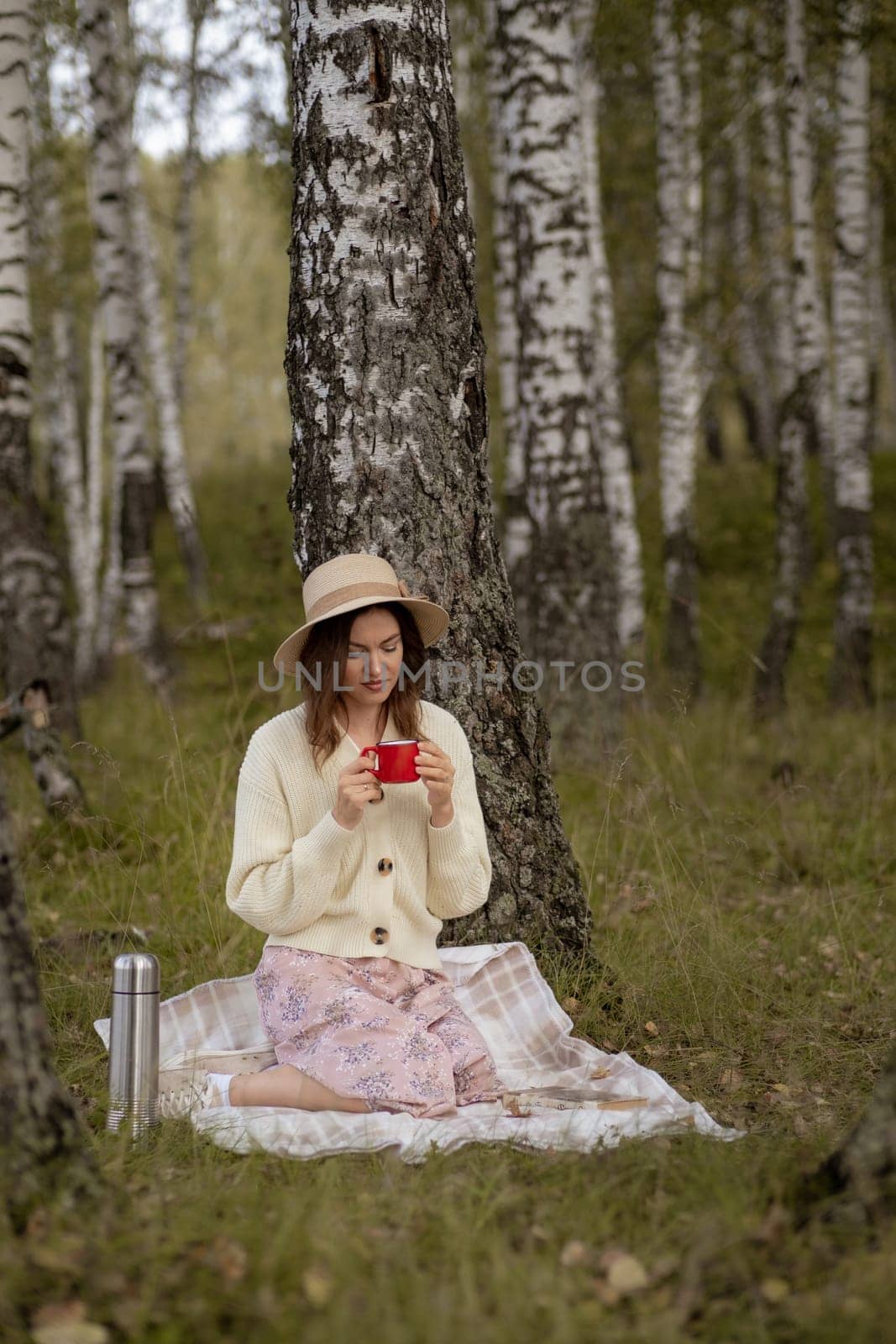 A young beautiful woman in a dress and a round hat reads a book by AnatoliiFoto