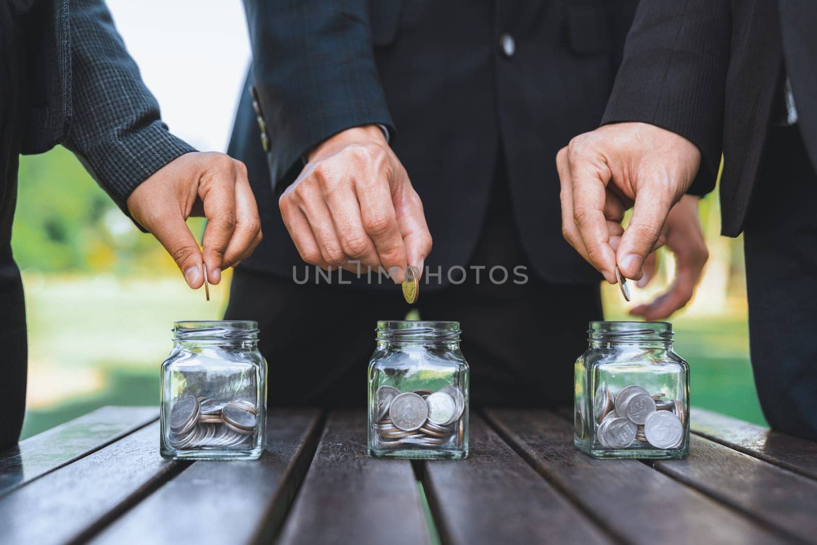 Business people put coin to money saving glass jar on outdoor table as sustainable money growth investment or eco-subsidize. Green corporate promot and invest in environmental awareness. Gyre