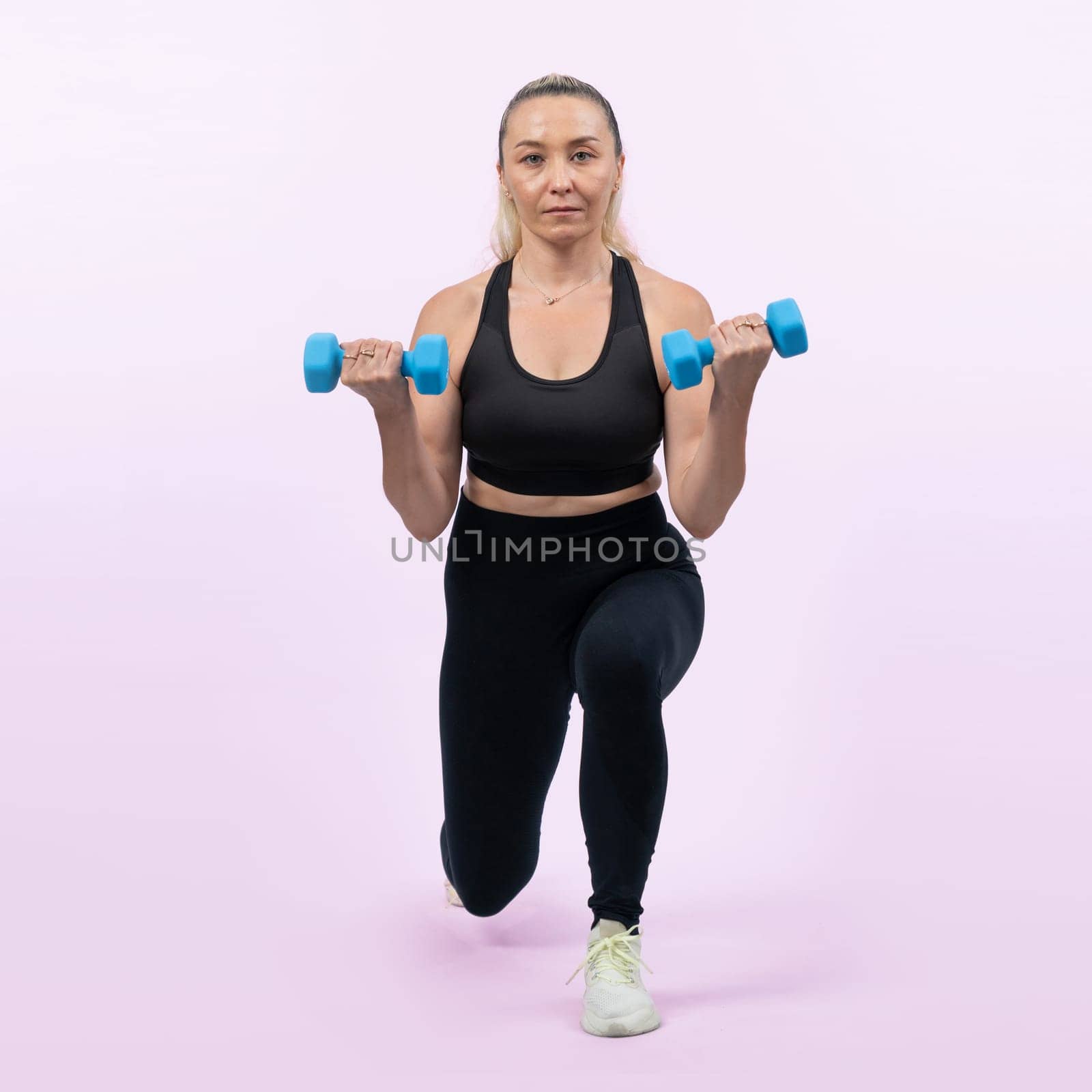 Full body length shot active and sporty senior woman lifting dumbbell during weight training workout on isolated background. Healthy active physique and body care lifestyle for pensioner. Clout