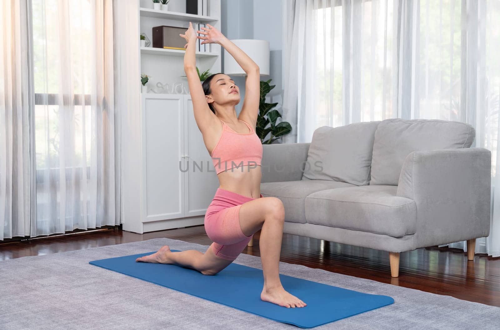 Asian woman in sportswear doing yoga exercise on fitness mat. Vigorous by biancoblue