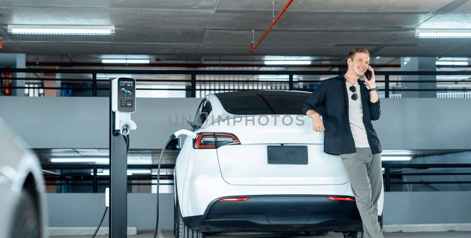 Young man travel with EV electric car to shopping center parking lot innards by biancoblue