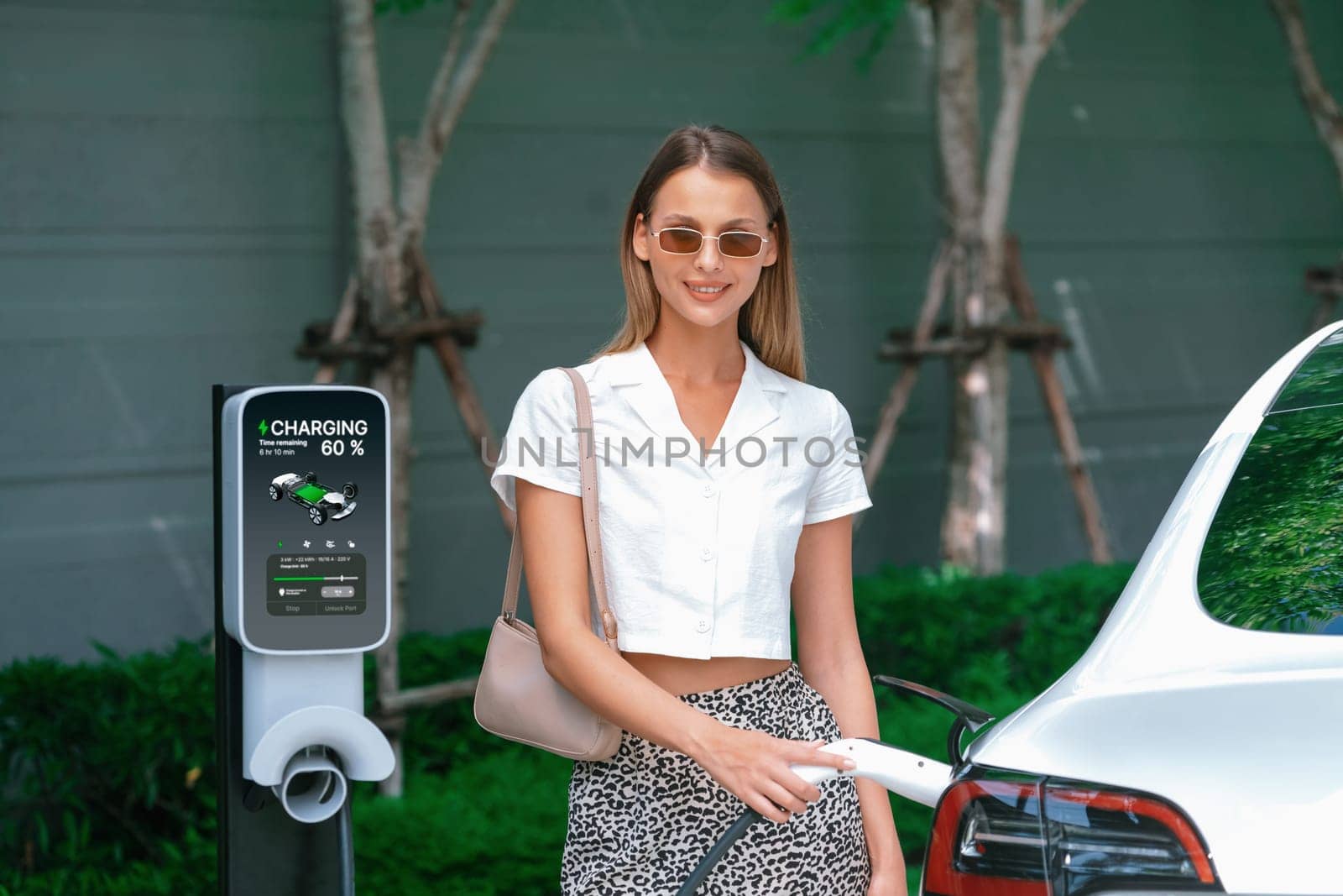 Young woman travel with EV electric car in green sustainable city innards by biancoblue