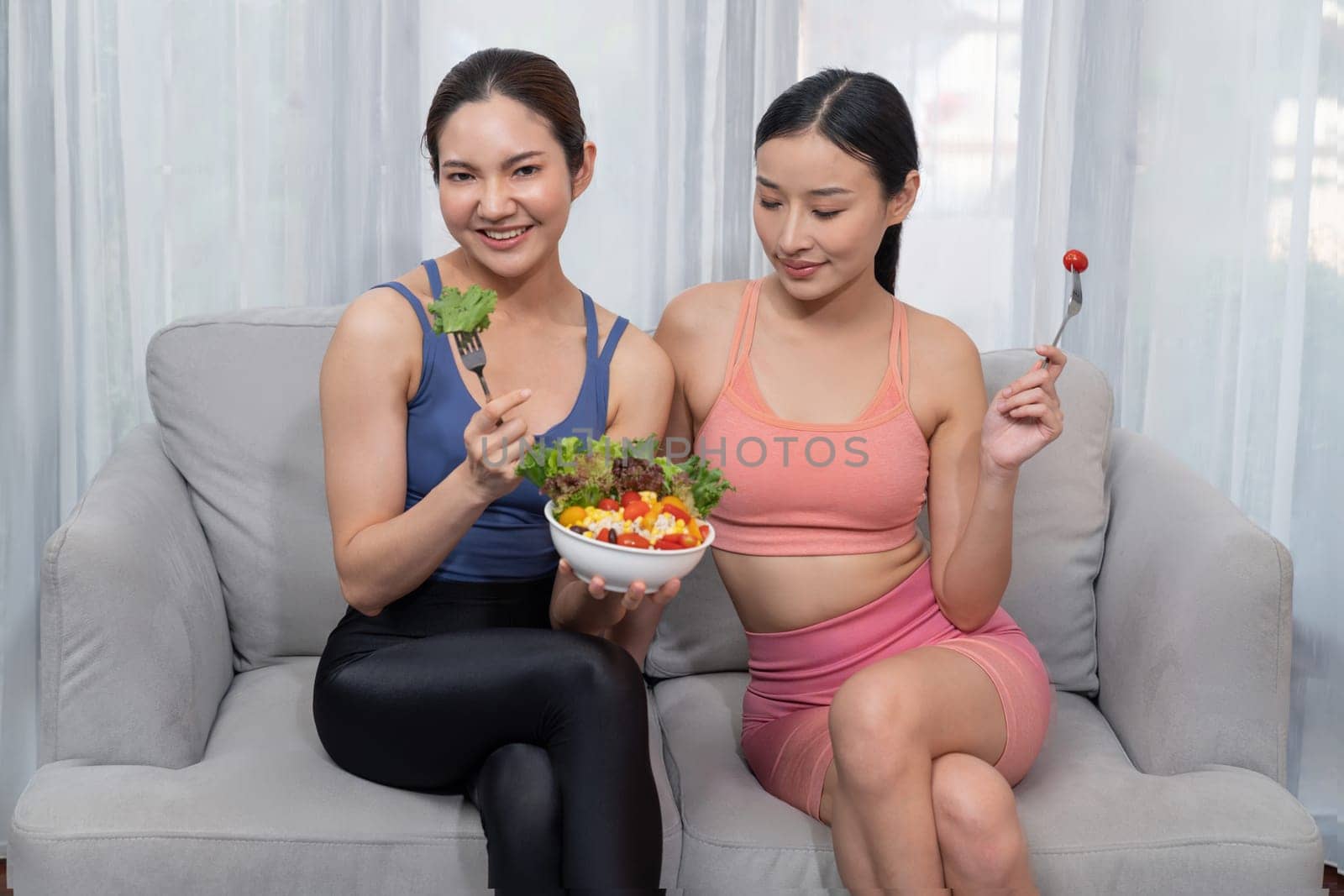 Young sporty Asian women in sportswear holding salad bowl together. Vigorous by biancoblue