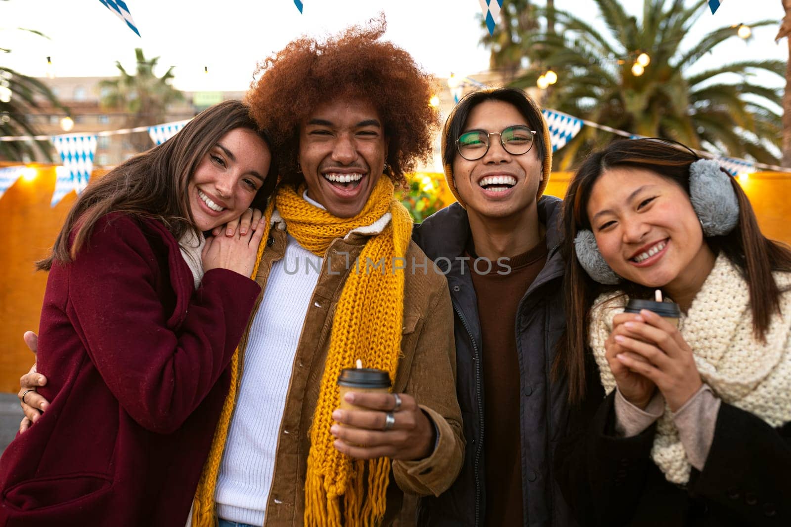 Happy and cheerful multiracial group of college student friends looking at camera smiling on a sunny winter day outdoors by Hoverstock
