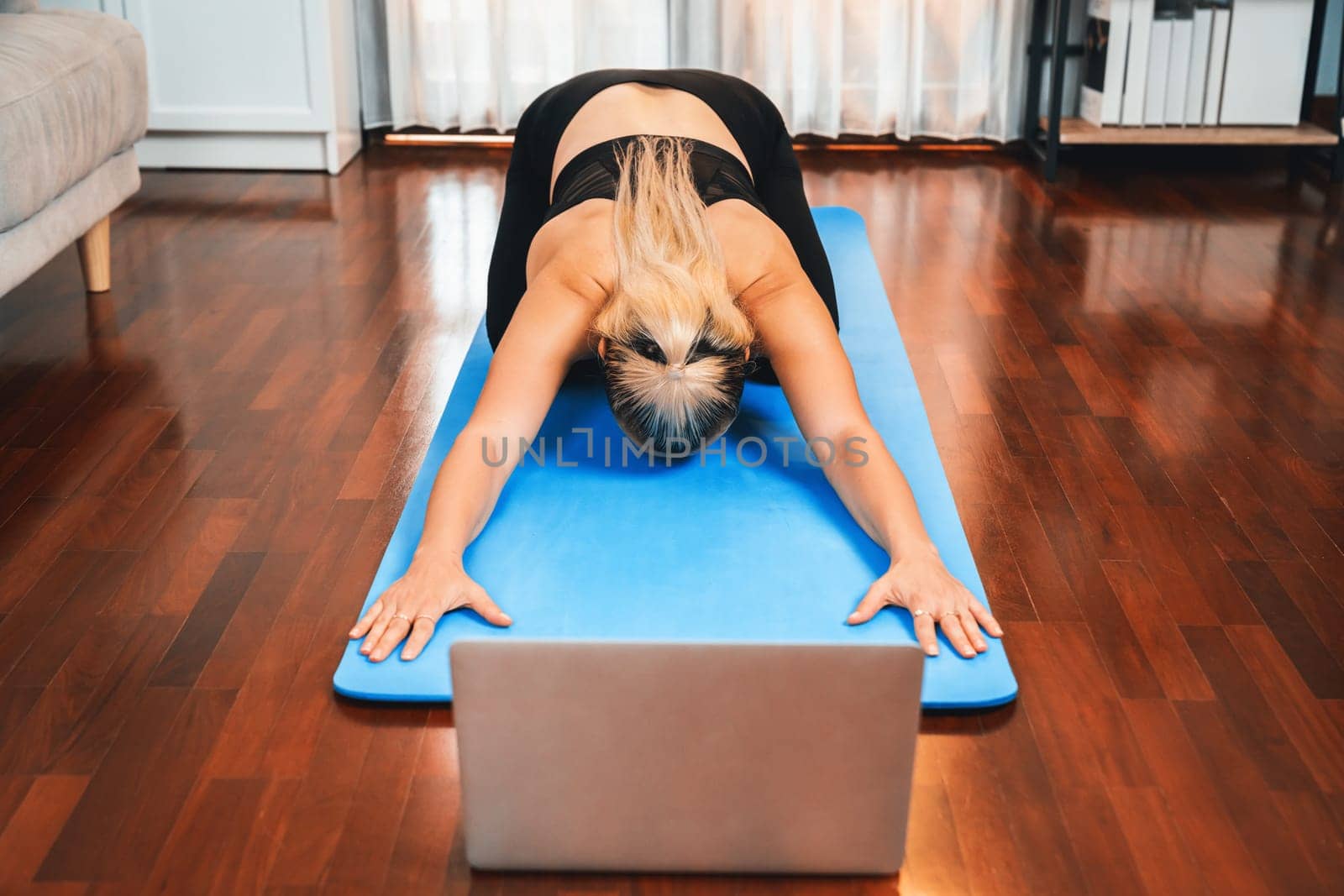 Senior woman in sportswear being doing yoga in meditation posture on exercising mat at home. Healthy senior pensioner lifestyle with peaceful mind and serenity. Clout