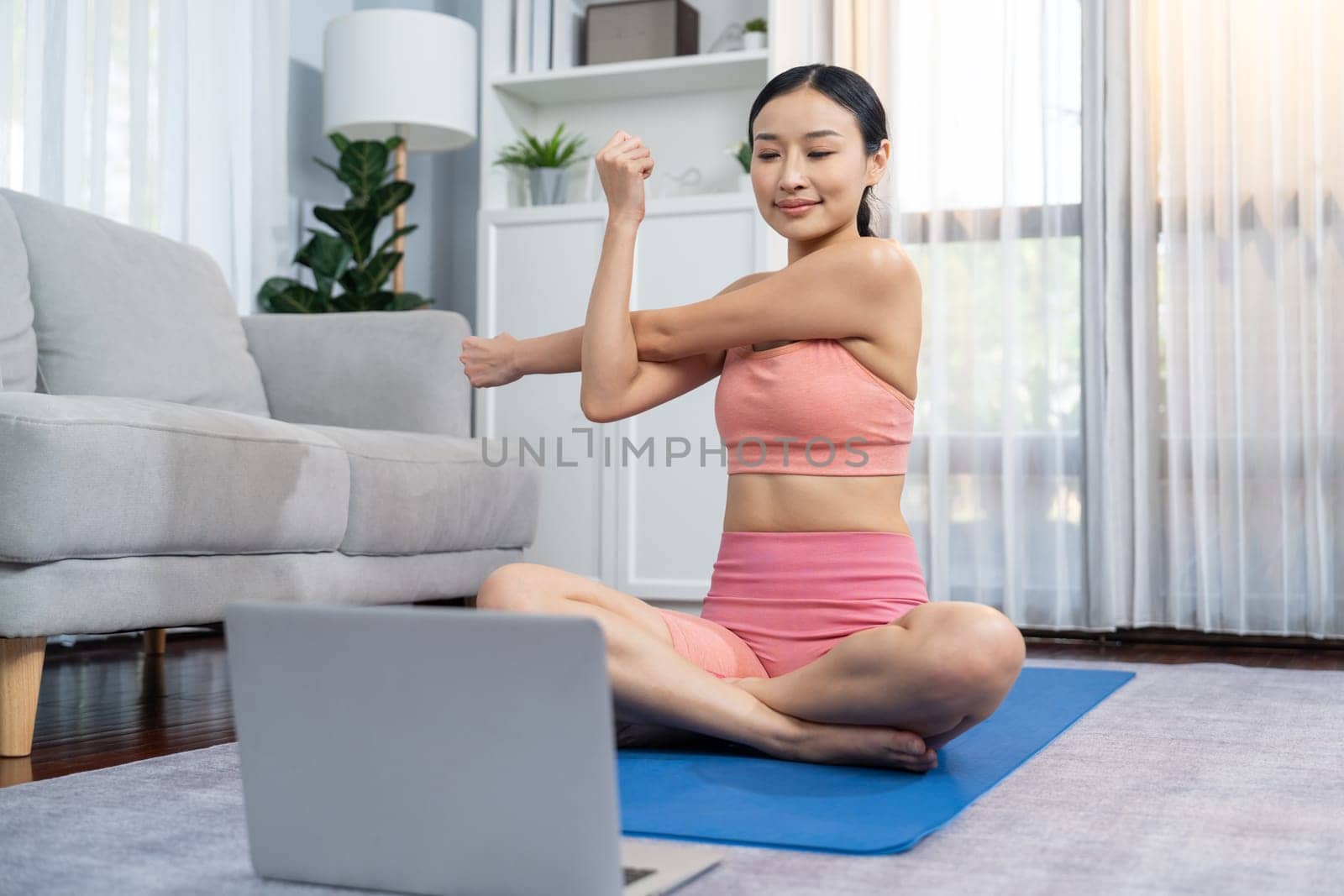 Asian woman in sportswear and yoga exercise on fitness mat with laptop. Vigorous by biancoblue