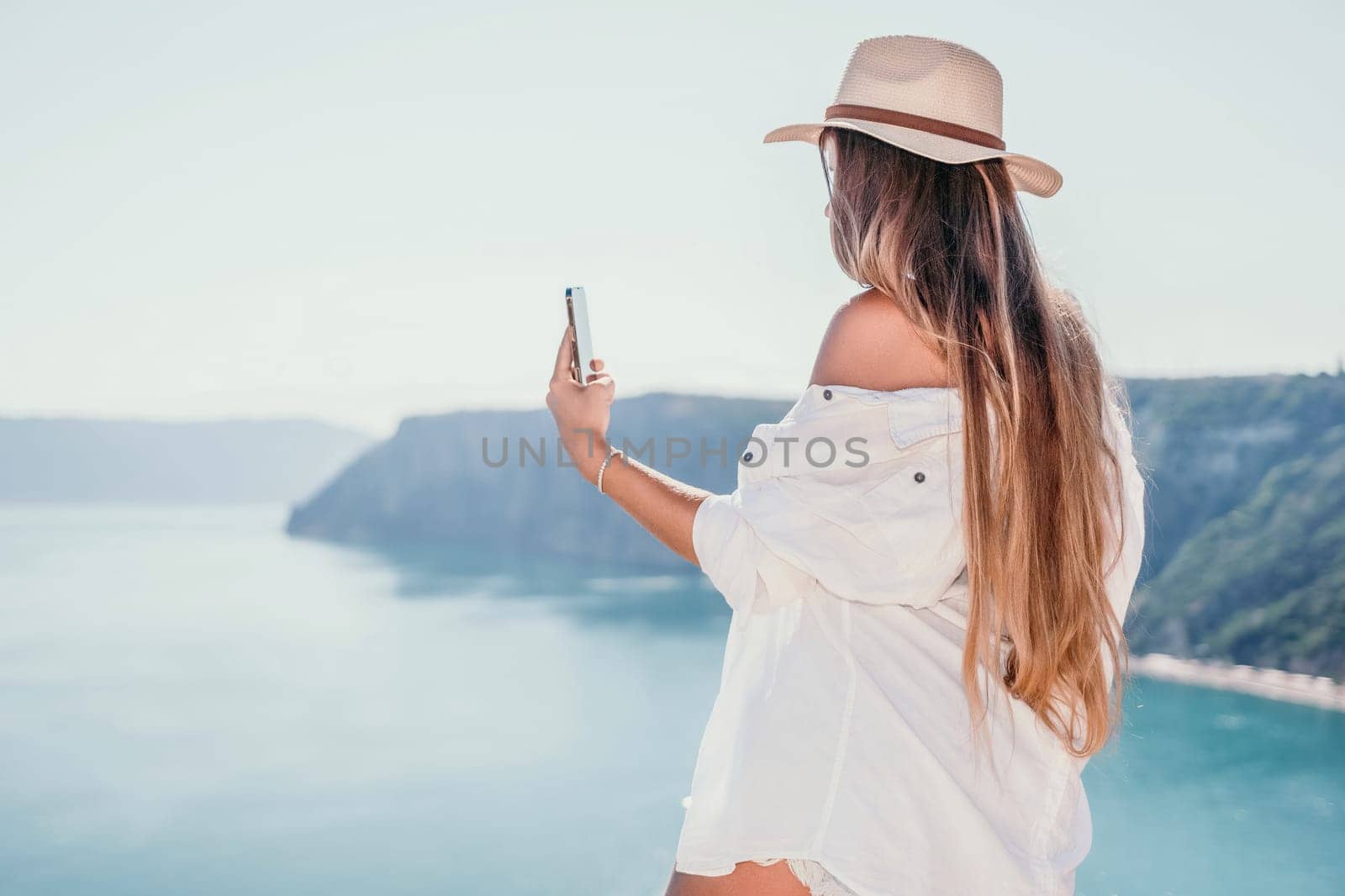 Digital nomad, Business woman working on laptop by the sea. Pretty lady typing on computer by the sea at sunset, makes a business transaction online from a distance. Freelance remote work on vacation