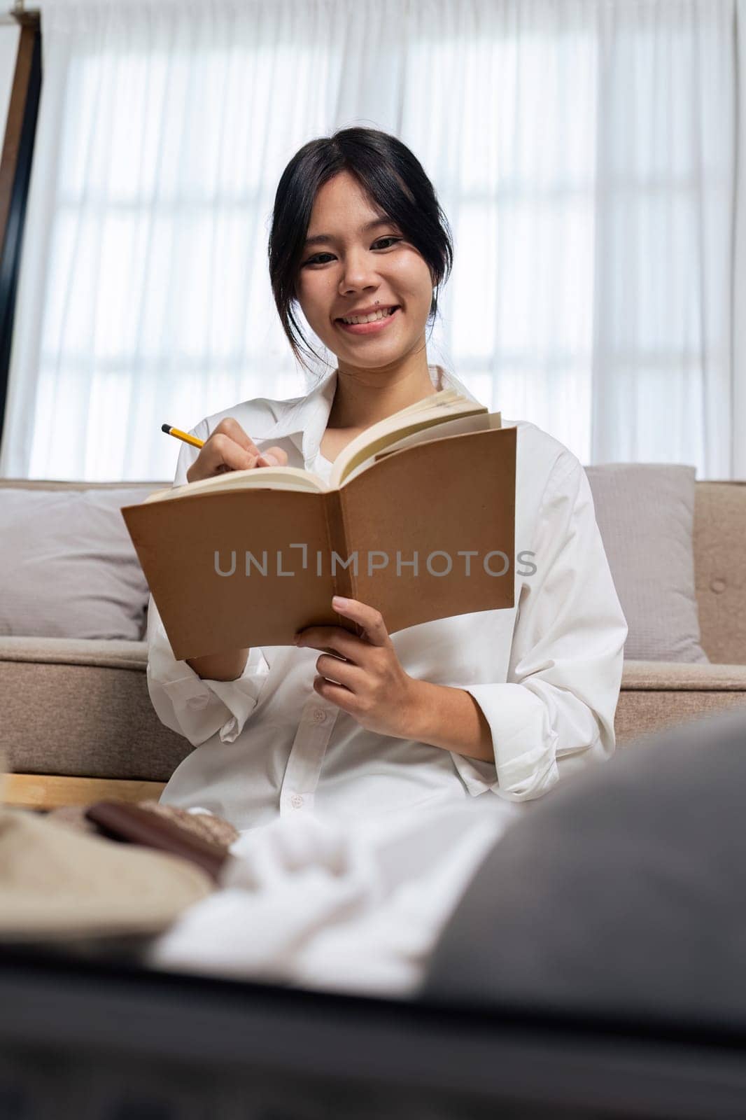 Young woman check baggage lists on notebook to prepare for traveling trip.