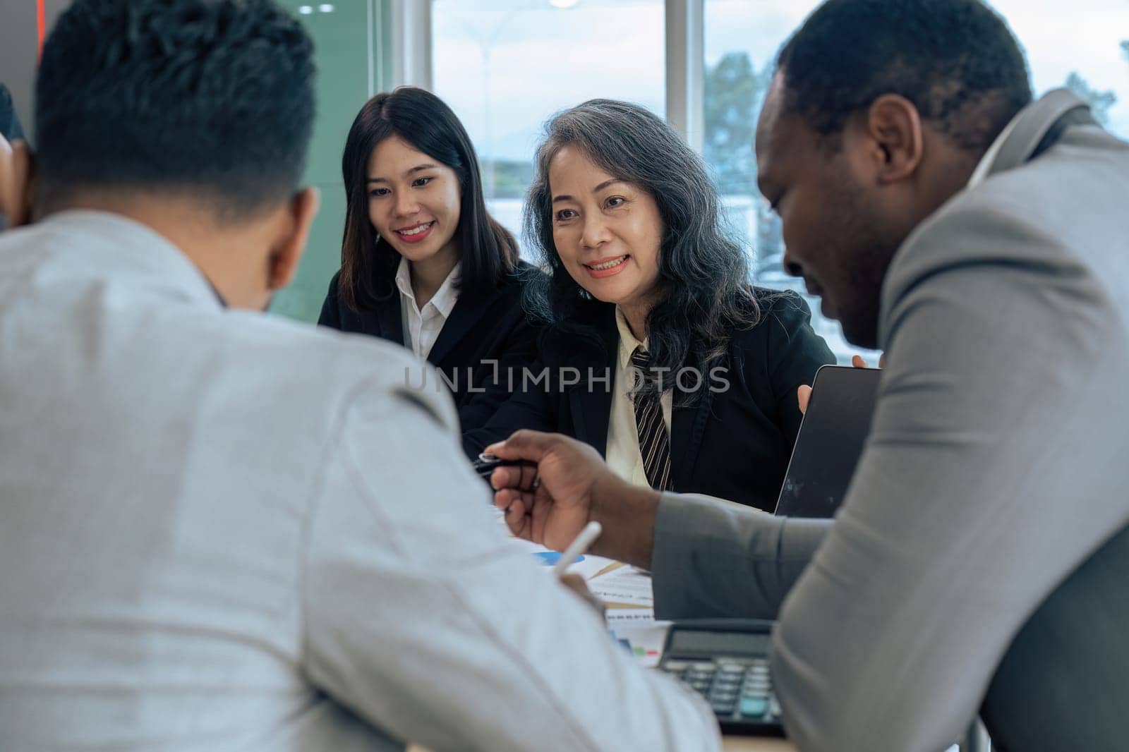 Female senior businessman brainstorming about marketing strategy report with diverse coworkers team.