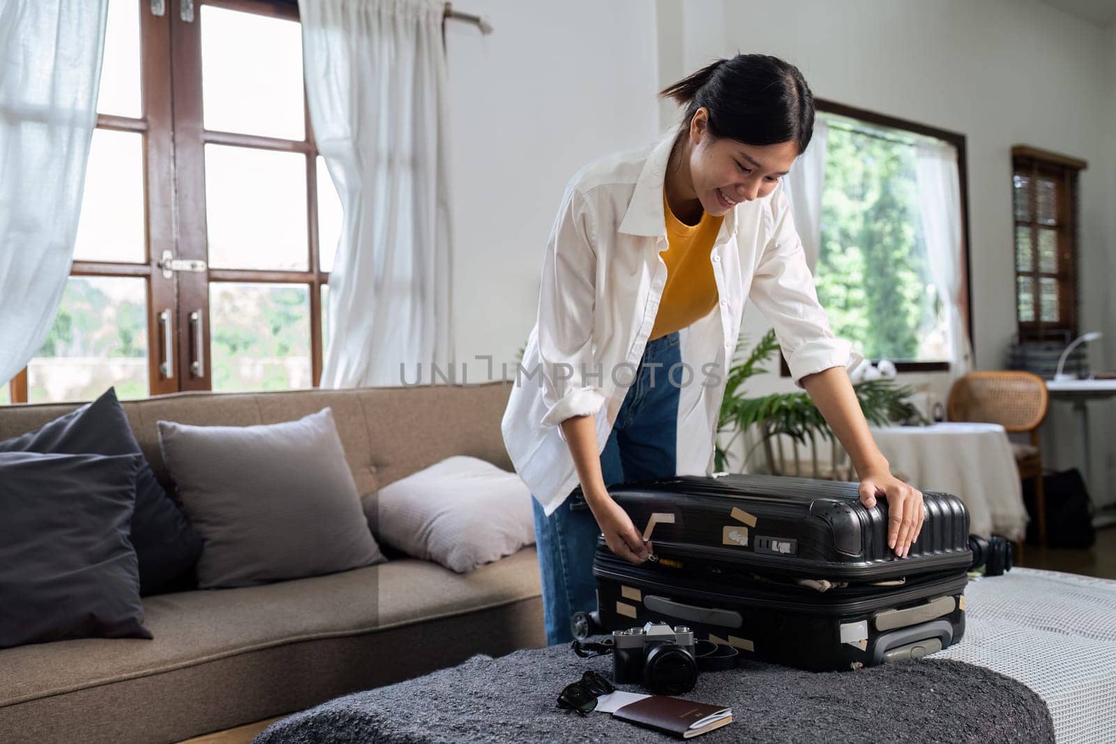 Young woman sit in floor and preparation suitcase for travelling at weekend trip.