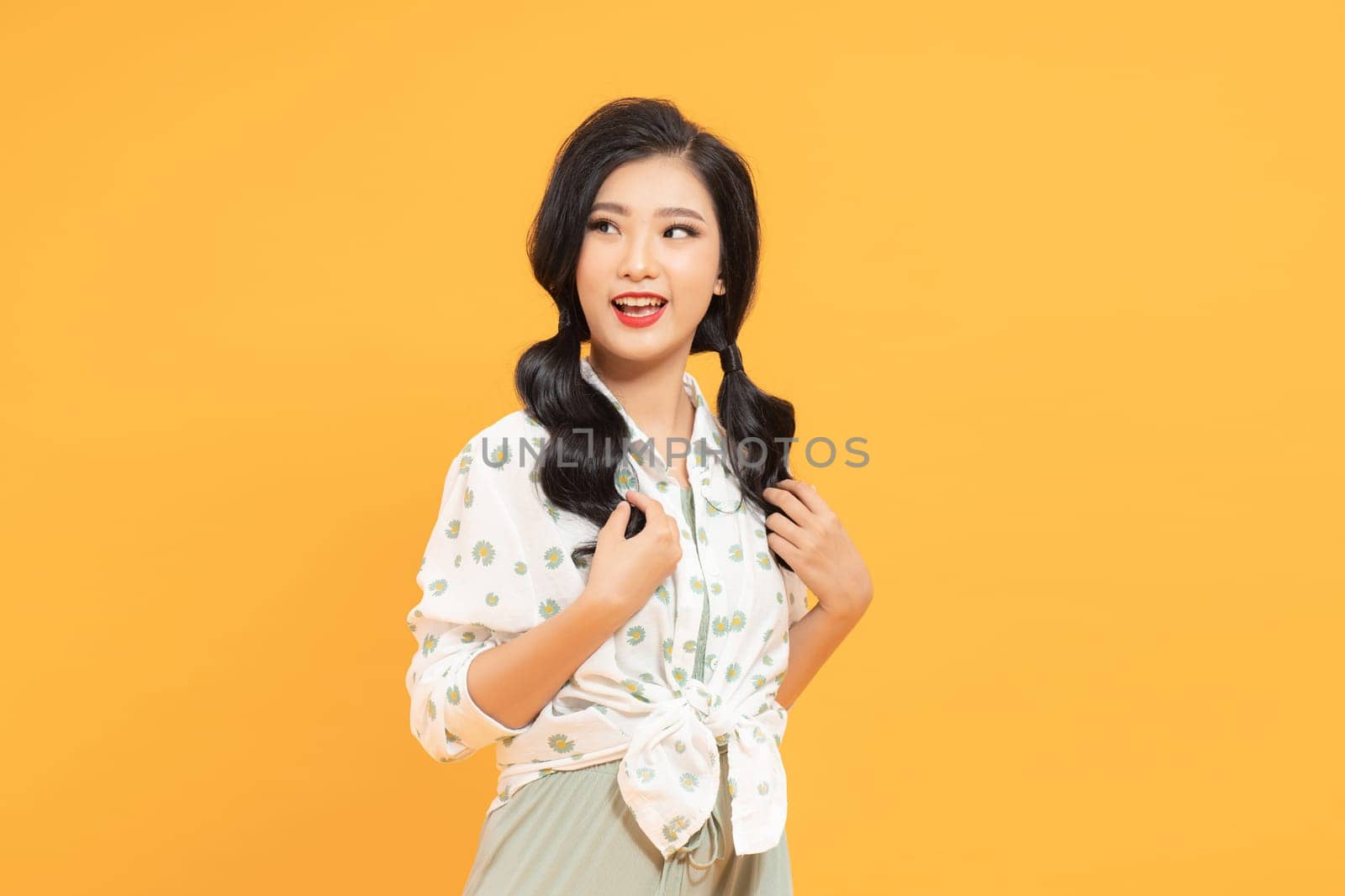 Asian young cool woman with pigtails hairstyle in casual trendy clothes on yellow background by makidotvn