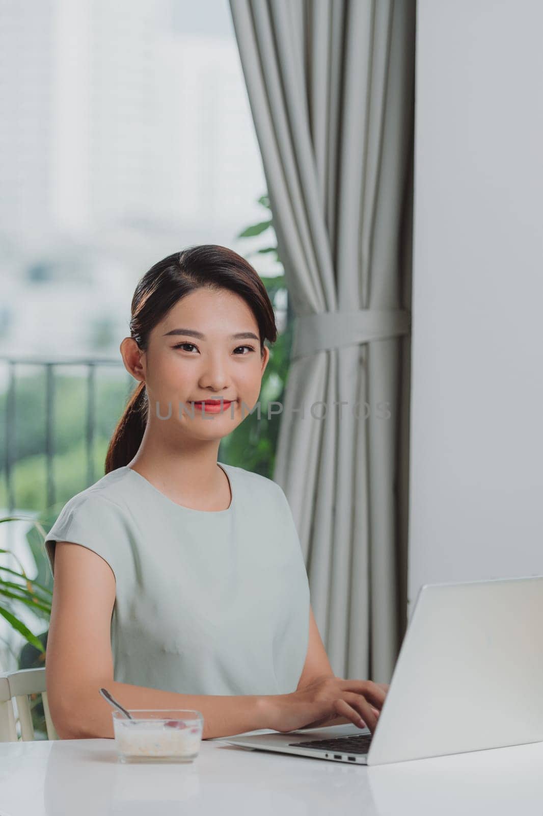 Female freelancer drinking juice while working on laptop at home