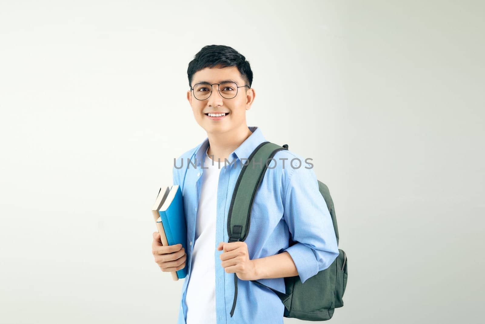 Young smiley student holding books carrying backpack, isolated on a white background.