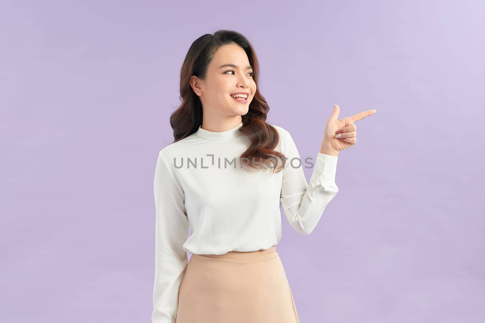 Asian young woman standing makes gesture fingers point upwards above presenting product something