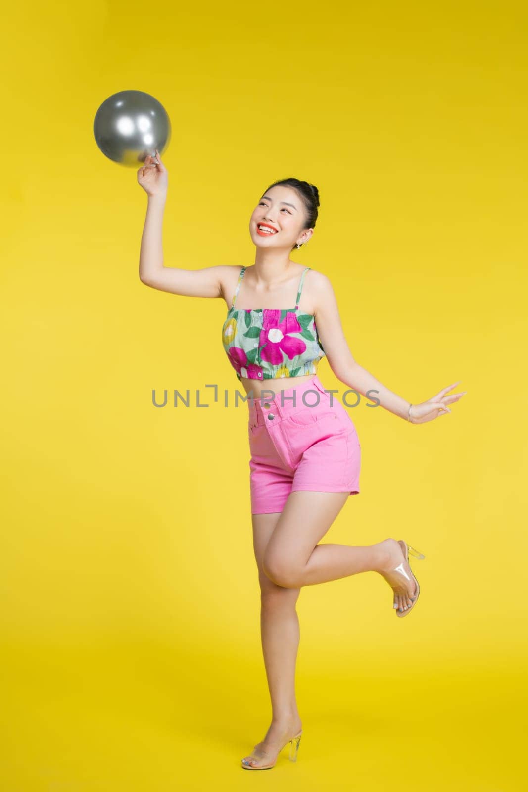 Smiling beautiful young asian woman dancing with silver balloons.  by makidotvn