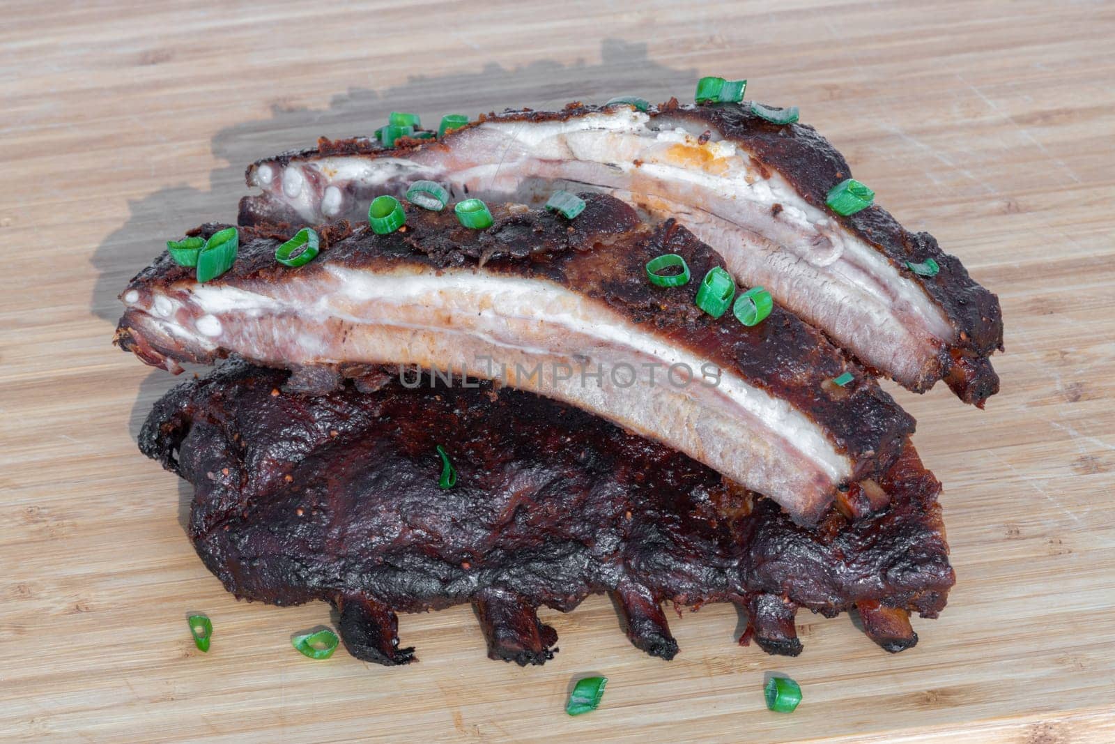 Indulge in succulent grilled BBQ ribs adorned with fresh green onions, an ideal dish for any enthusiastic meat lover