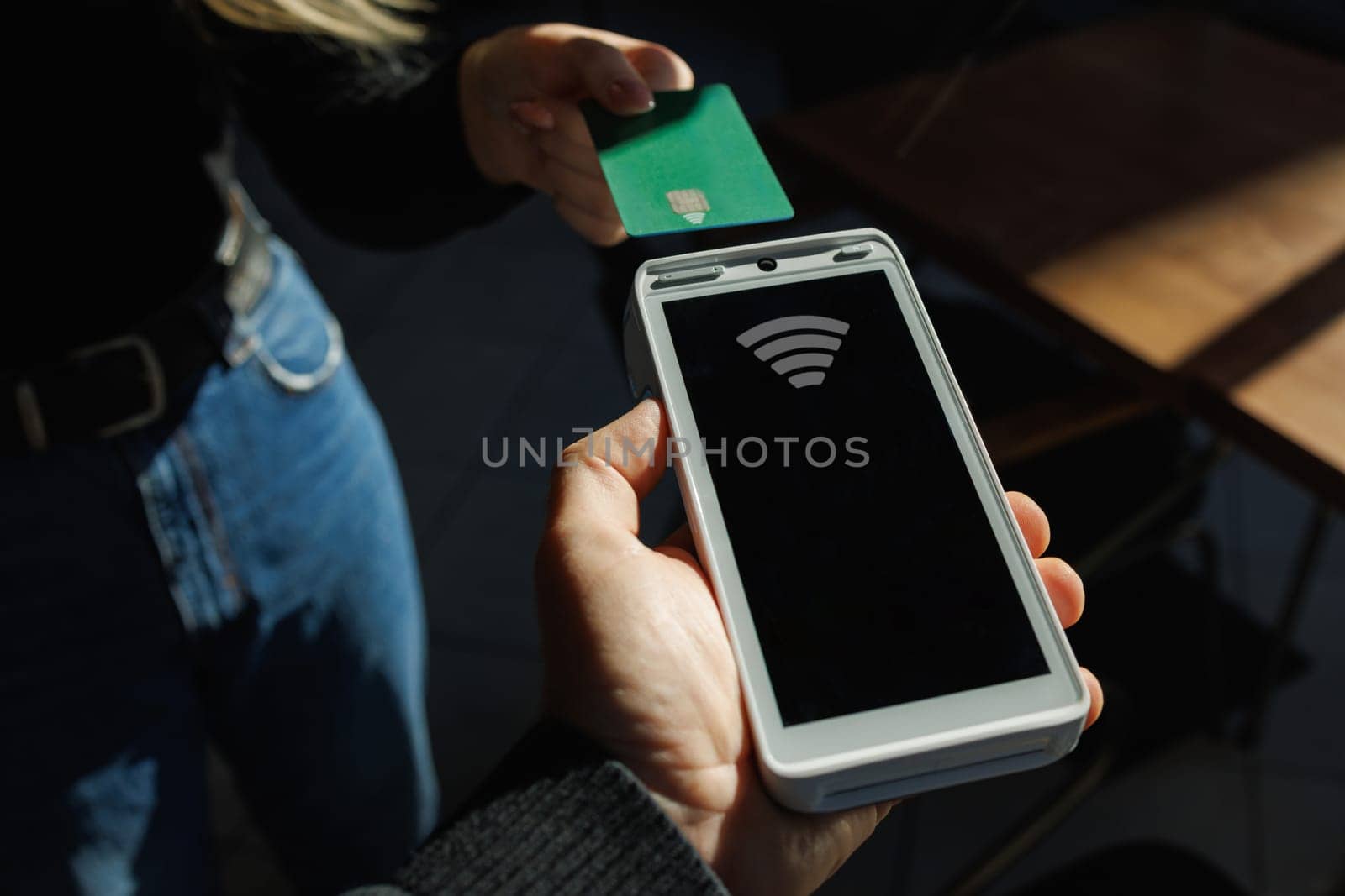 Close Up of a Masculine Hand Holding a Credit Card with an NFC Payment Technology Used for Paying . Customer Uses Debit Card to Pay Through Bank Terminal.