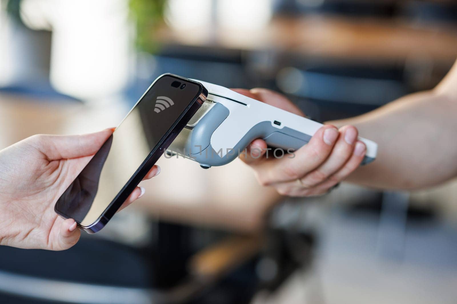 Close Up of a Customer Making a Secure Contactless Online Payment Using a Smartphone with a Credit Card Banking NFC App. Modern Shopper Buying Organic Fruits and Vegetables From a Farmers Market Stall