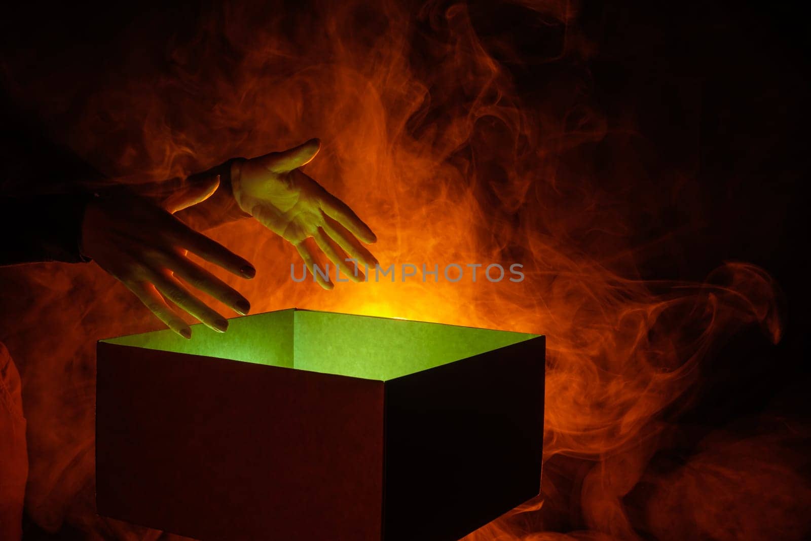 human hands taking out surprise from mysterious box on dark red background surrounded by smoke, mystery box