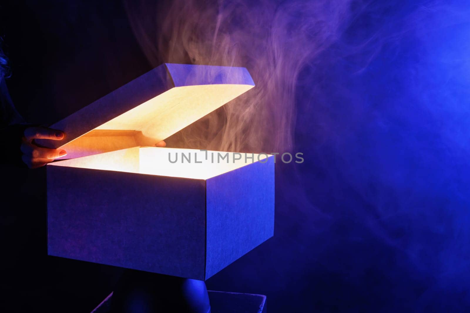 human hands taking out surprise from mysterious box on dark red background surrounded by smoke, mystery box