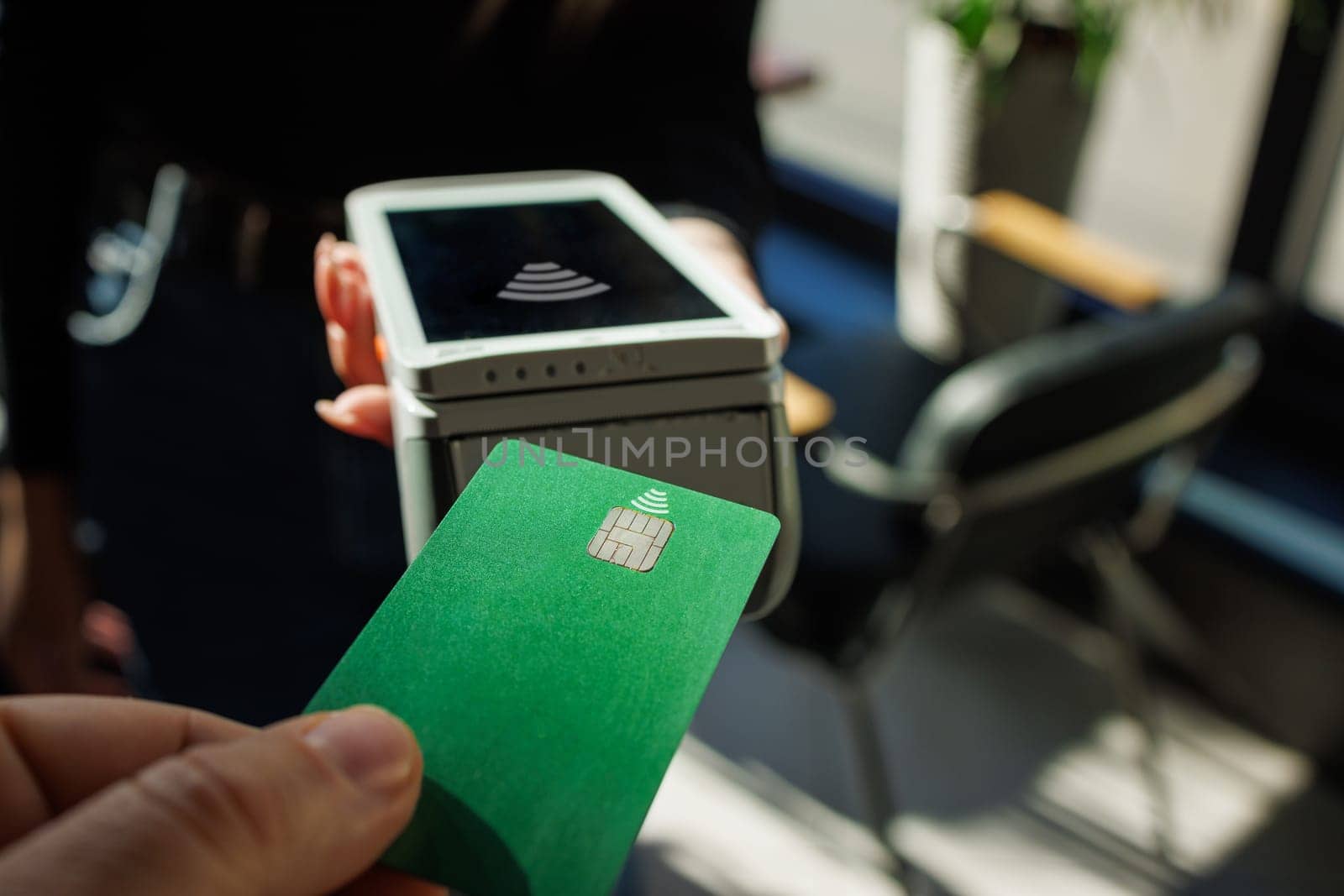 Close Up of a Masculine Hand Holding a Credit Card with an NFC Payment Technology Used for Paying . Customer Uses Debit Card to Pay Through Bank Terminal.