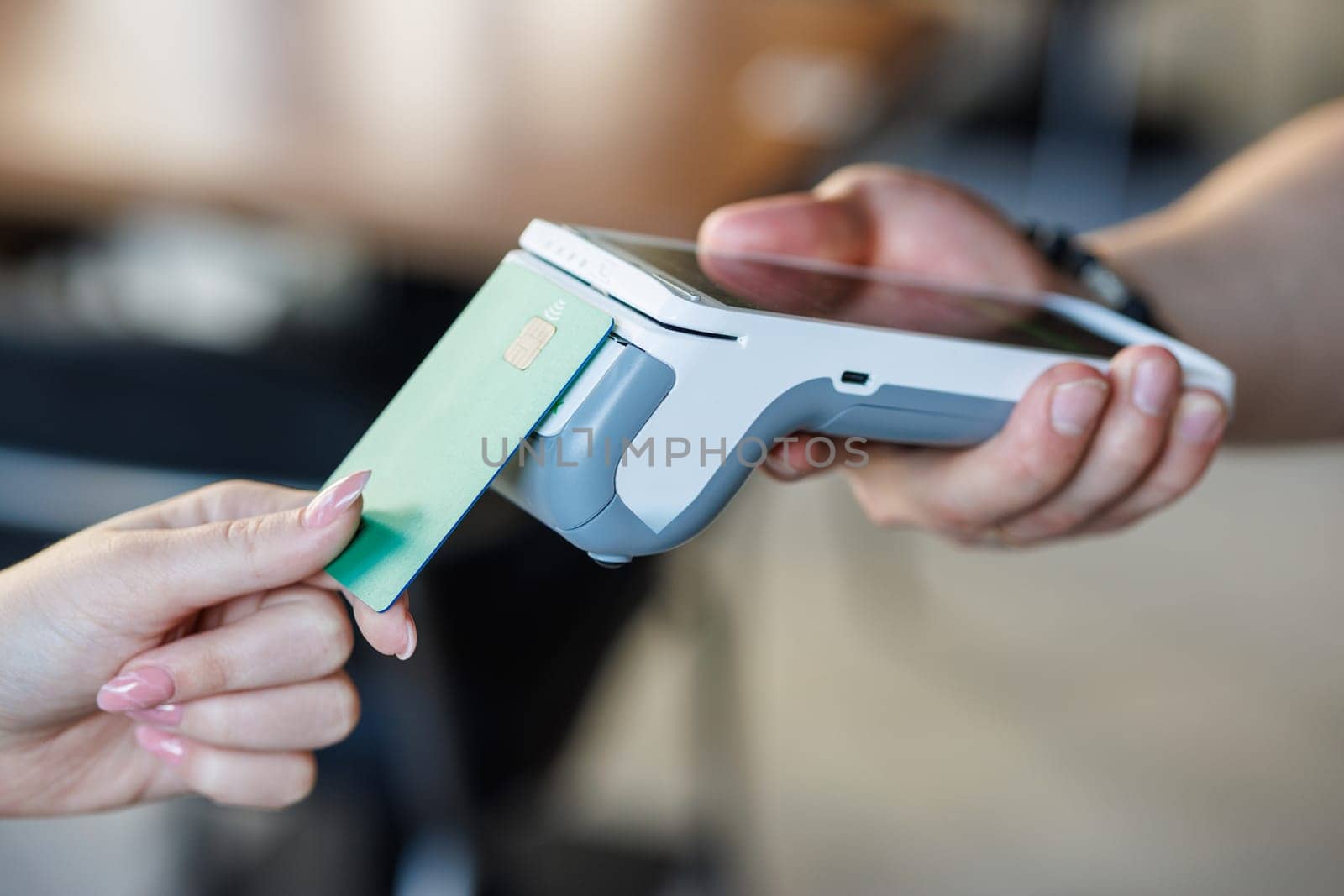 Customer paying with credit card using POS machine indoors, closeup, Customer Uses Debit Card to Pay Through Bank Terminal