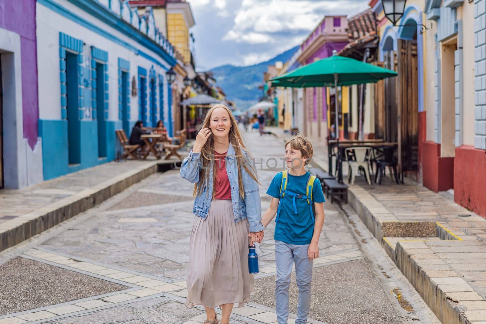 Mother and her son tourists walks through the colonial streets San Cristobal de las Casas, Mexico. Cultural exploration, architecture, and travel experience concept.