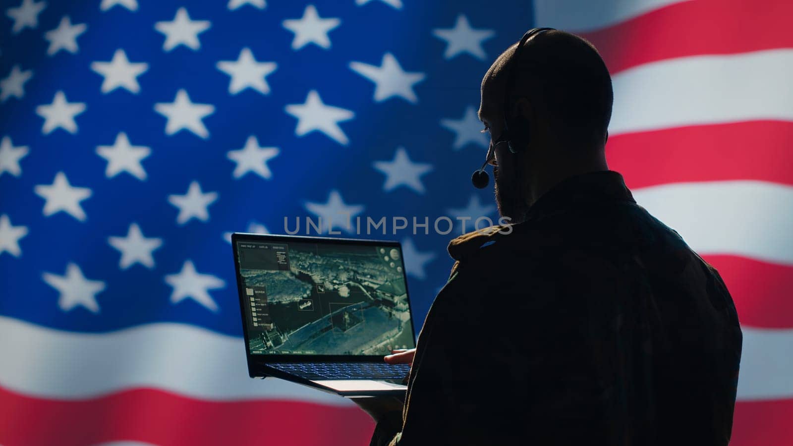 US Air Force dispatcher looking at surveillance transmission on device, relaying data to ground soldiers from control room using headset, isolated over United States flag background, camera A