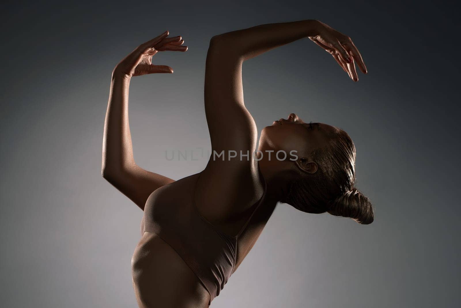 Graceful girl in ligerie with gold bodyart profile shot in the dark room