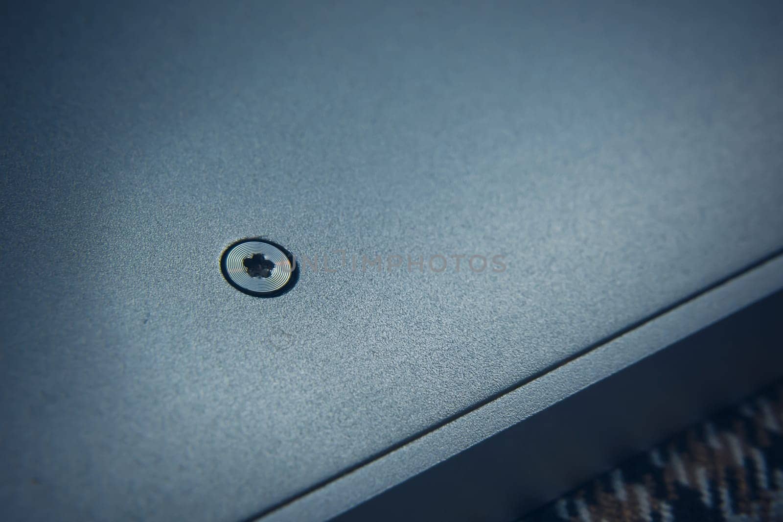 A detailed and closeup view of a single screw that is deeply embedded into a smoothly polished metallic surface