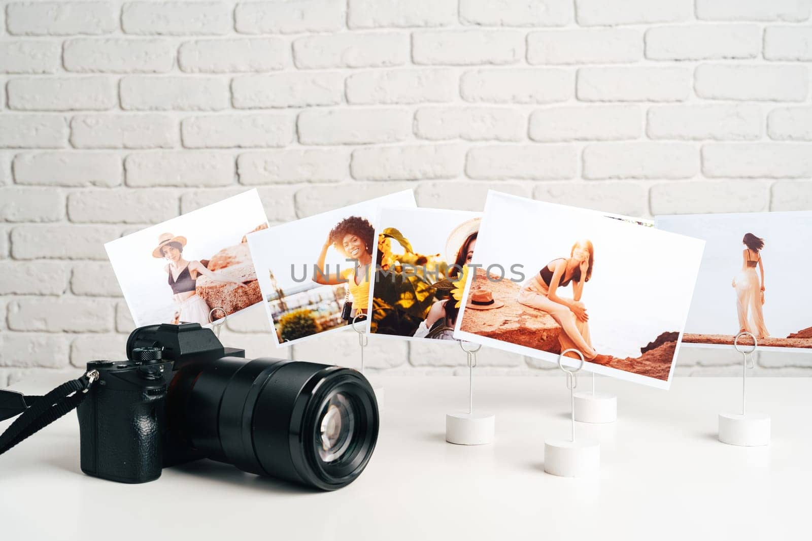 Camera and colorful printed photos of women on the desk close up