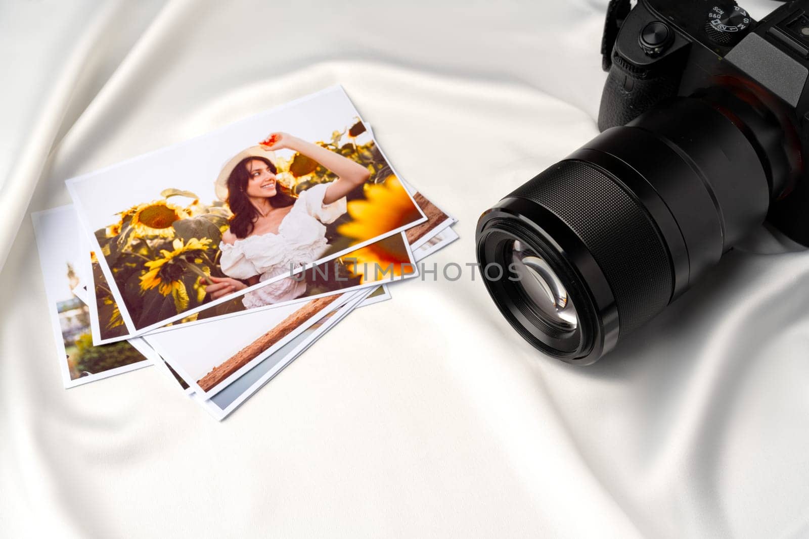 Camera and colorful printed photos of women on the desk close up