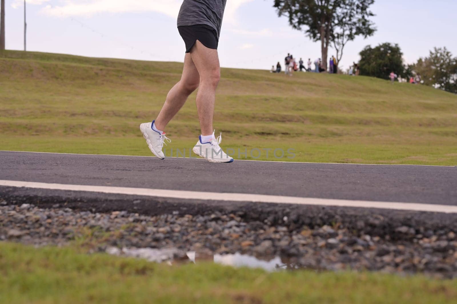 Close up of runner legs and feet moving along a paved path in an outdoor. Fitness and active lifestyle.
