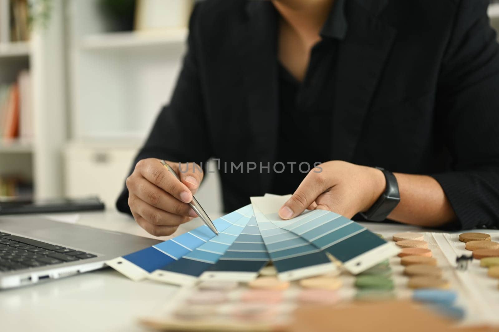 An interior designer reviewing a color chart while working on new design project at a desk.