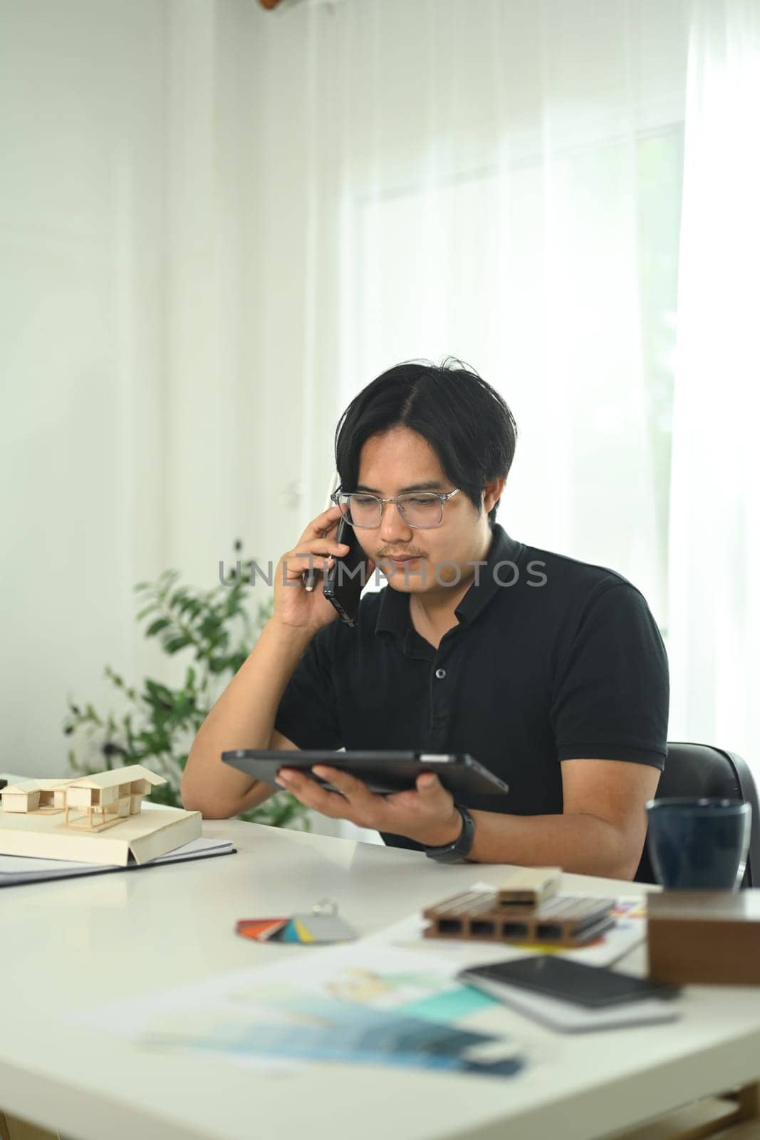 Professional architect discussing project plans over phone and using digital tablet in the office.