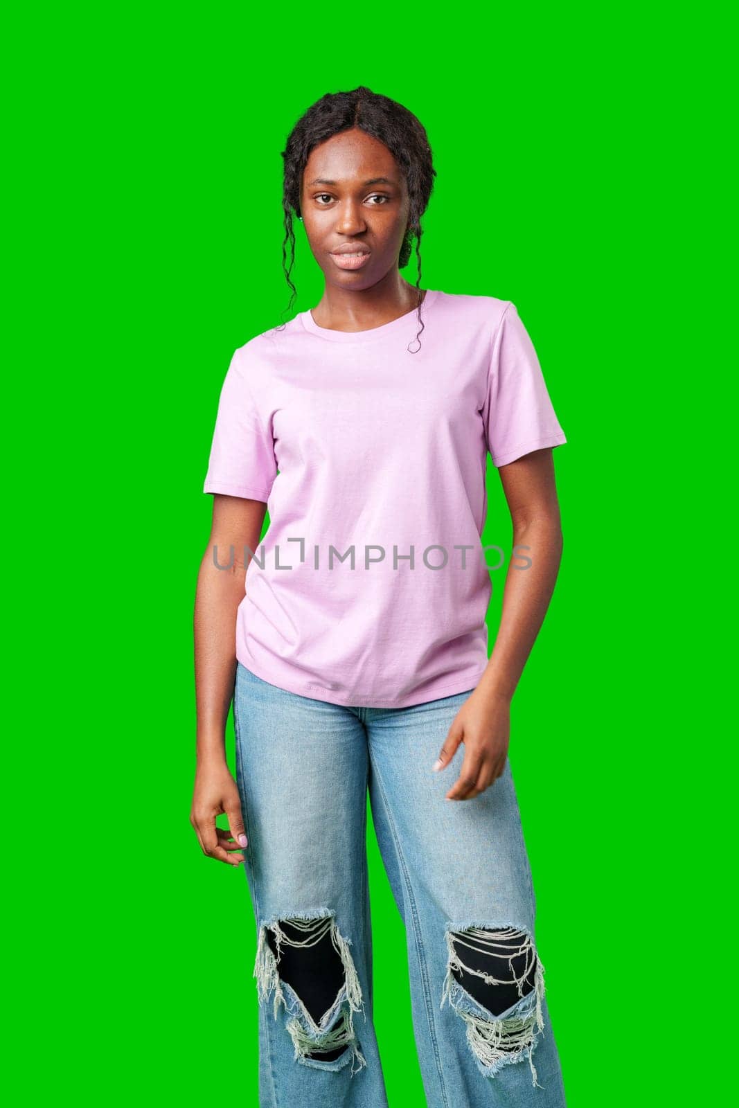 A joyful young woman smiling brightly while standing against a vivid green background in studio