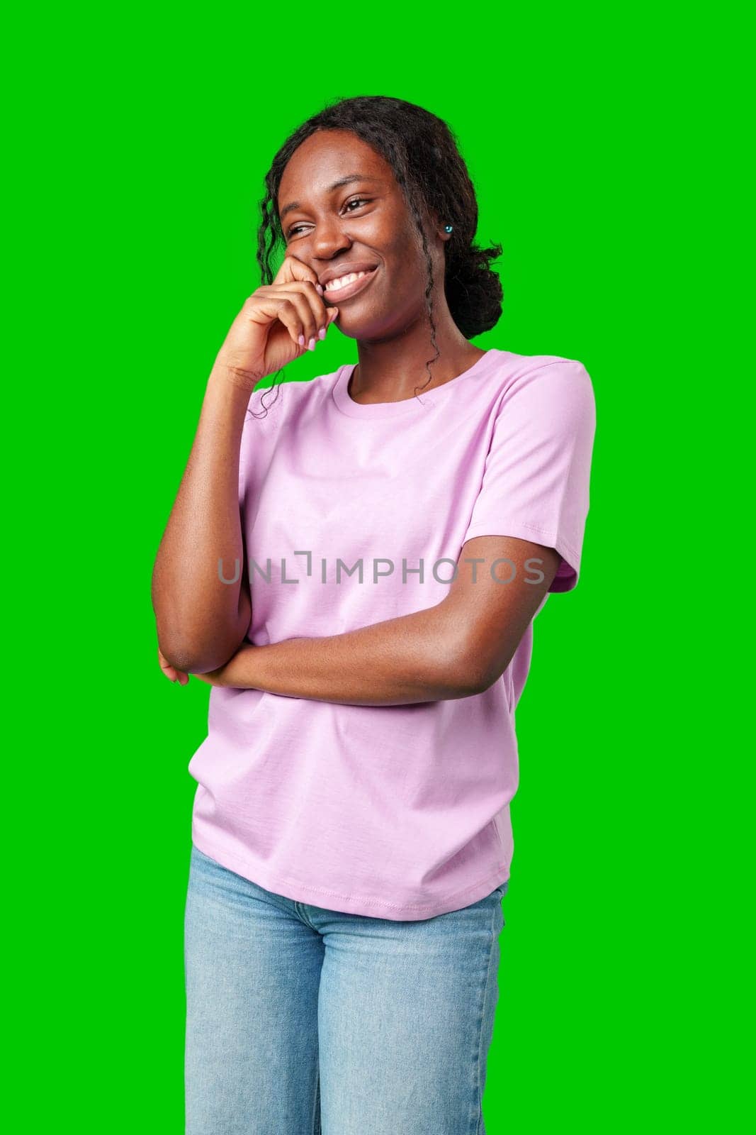 Happy young person laughing and playfully covering face while standing against a bright green background in studio