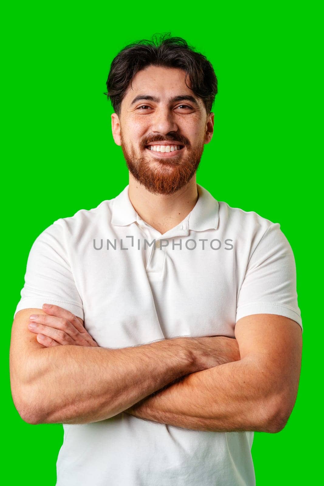 A smiling young man with a beard poses against a bright green background close up