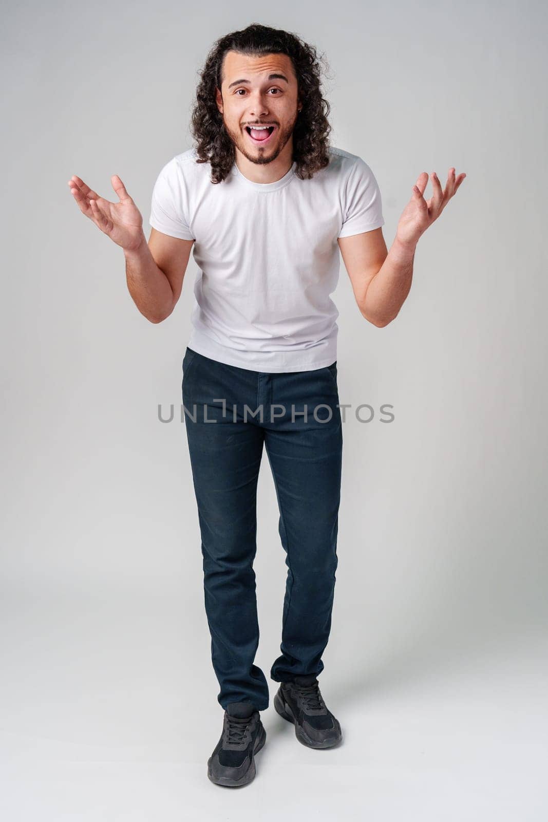 Young man with curly hair expresses surprise in a light-colored setting close up