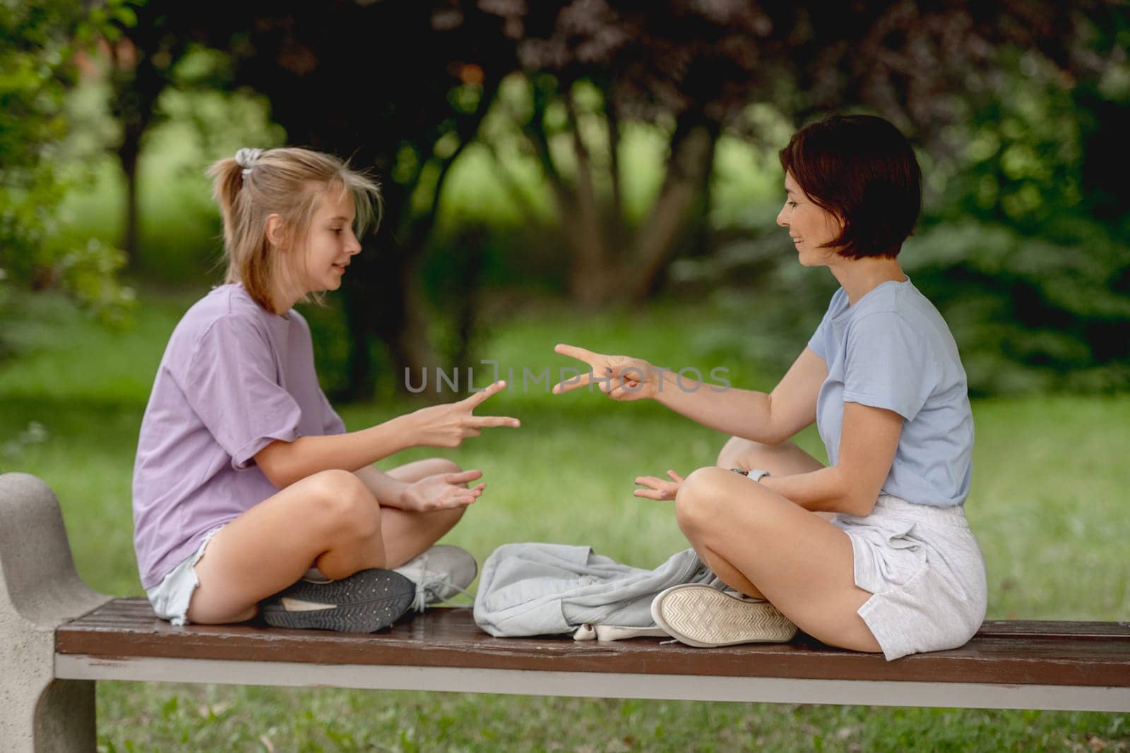 Mother And Daughter Happily Playing Rock, Paper, Scissors Outdoors