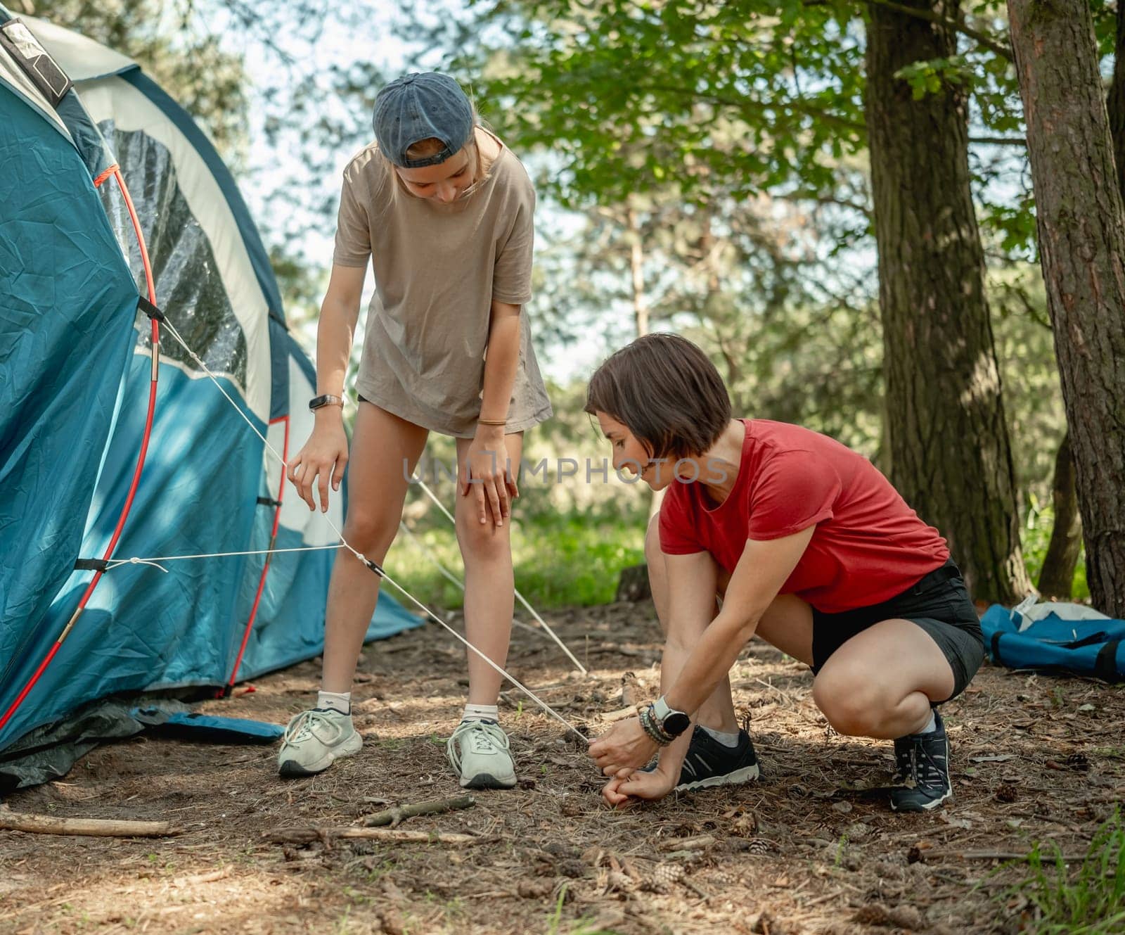Mother And Daughter Setting Up A Tent In The Forest For The Summer