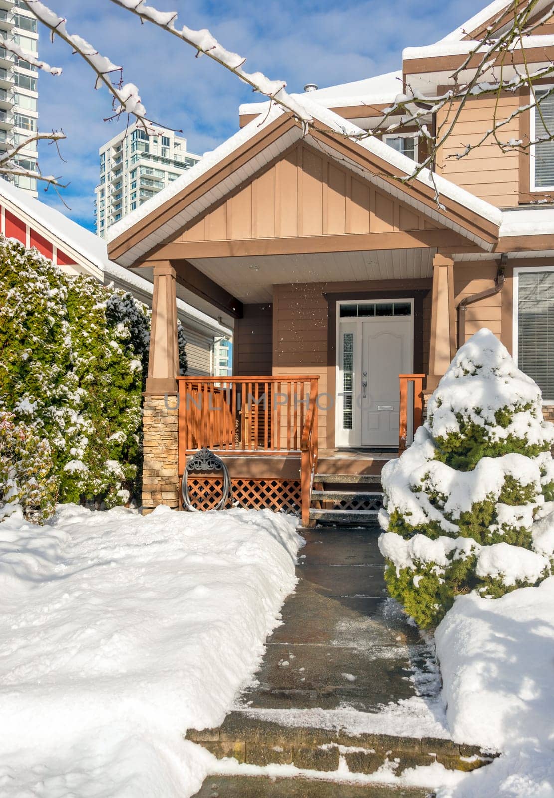 A perfect neighbourhood. Modern high-rise and private residential house in snow on winter season in British Columbia, Canada.