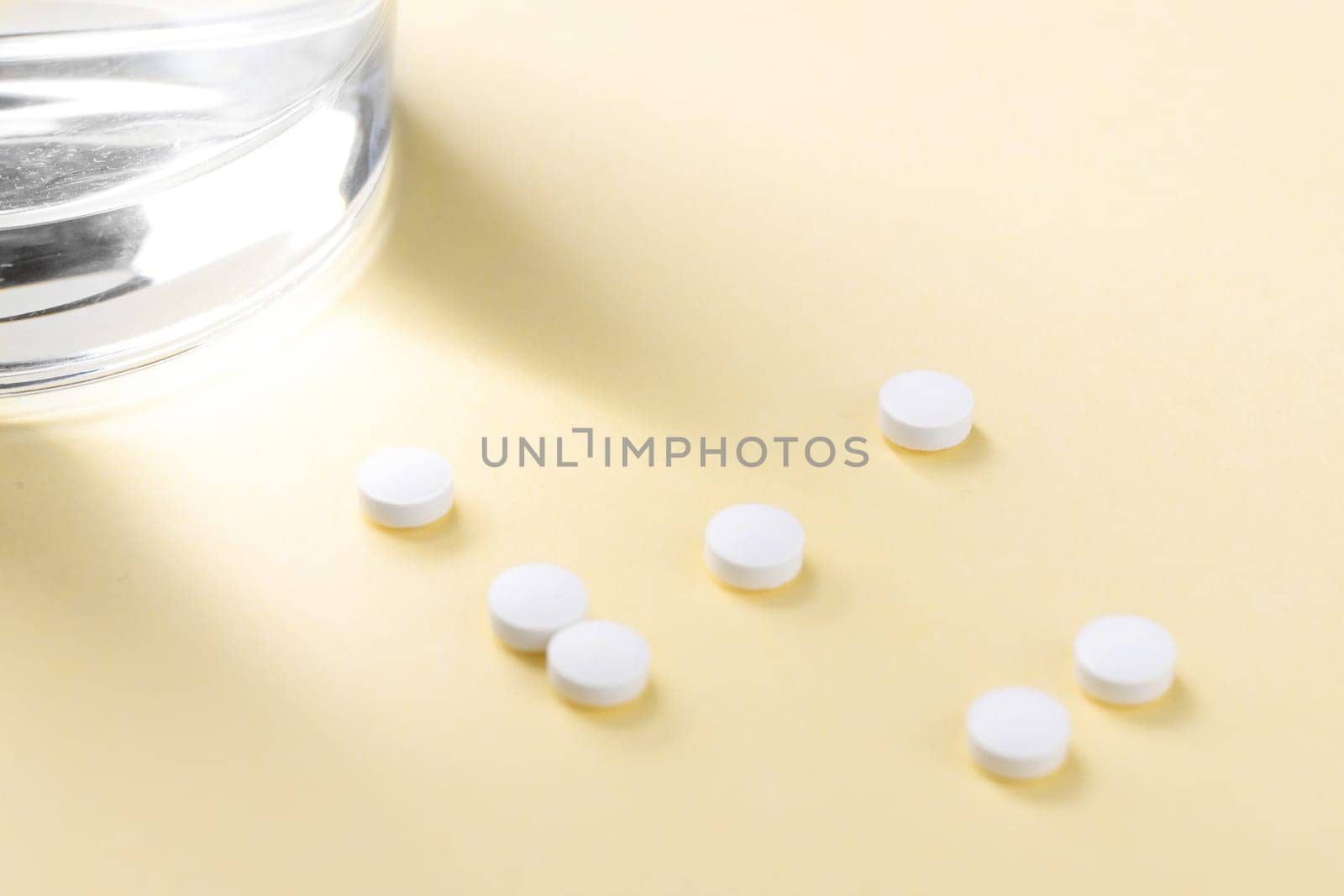 Tablets on the table next to a glass of water. Supporting the body with vitamins and dietary supplements.