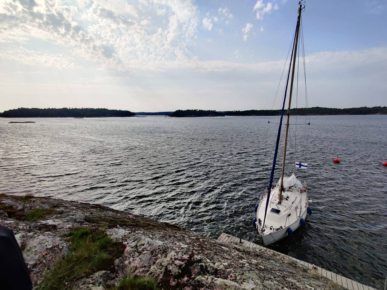 Sailboat tied to a mooring buoy at the harbor of the island in Finland, Baltic sea, Yacht in Shore marina in Baltic Sea, a safe anchorage for yachts and sail boats.