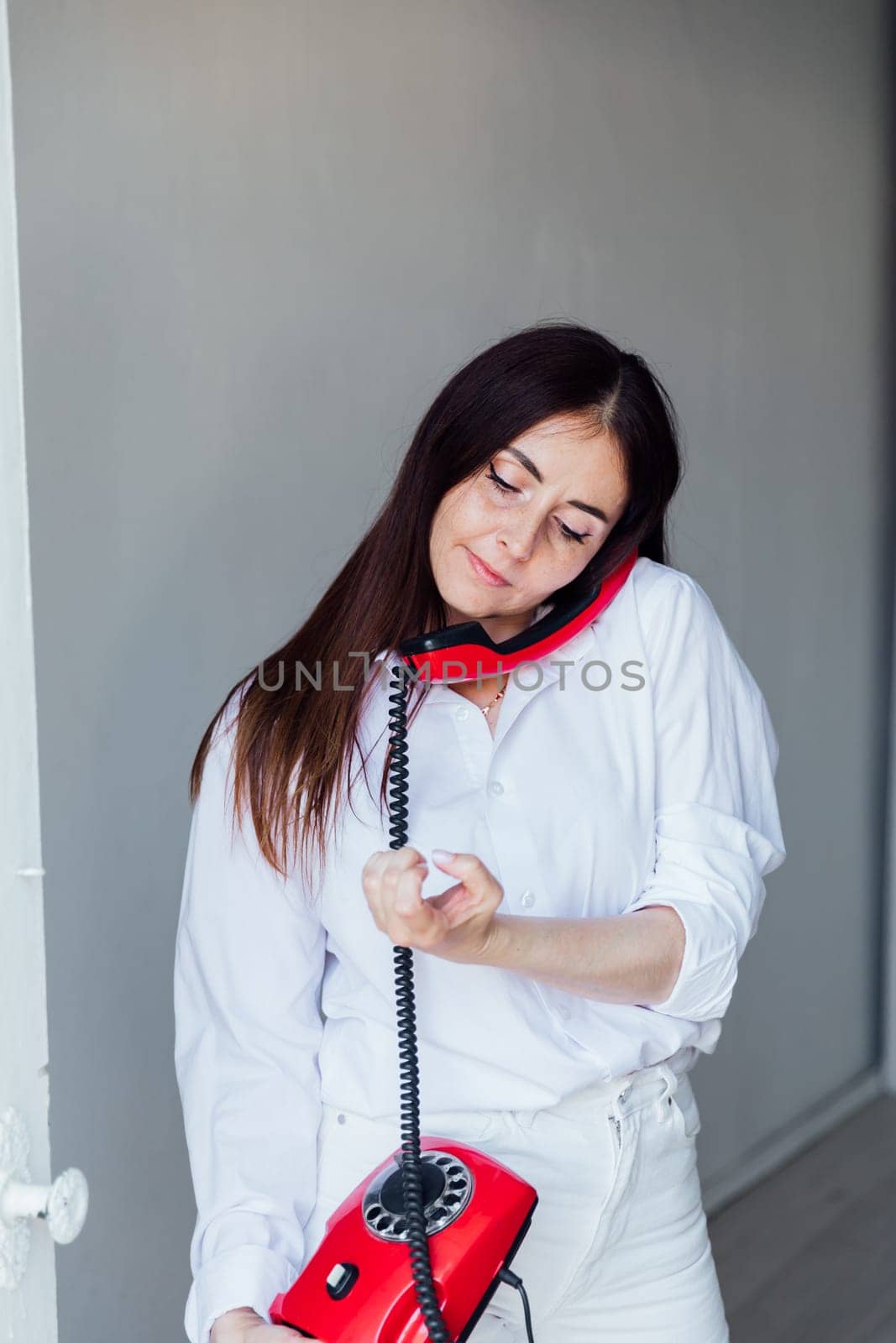brunette woman talking on old corded phone